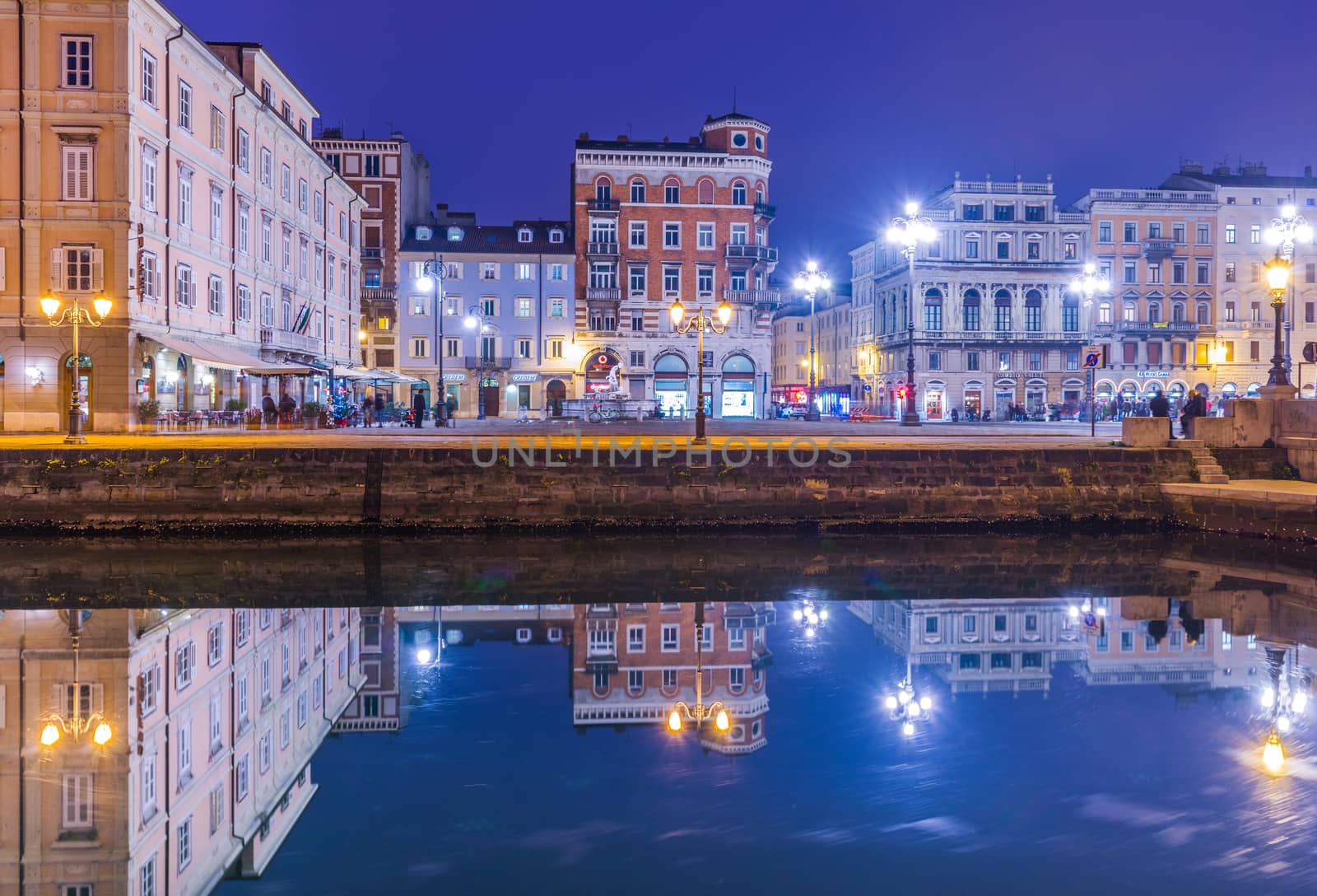 Trieste - December 2016, Italy: Night view of Trieste, old buildings mirror reflected in water, Grand Canal in Trieste city center
