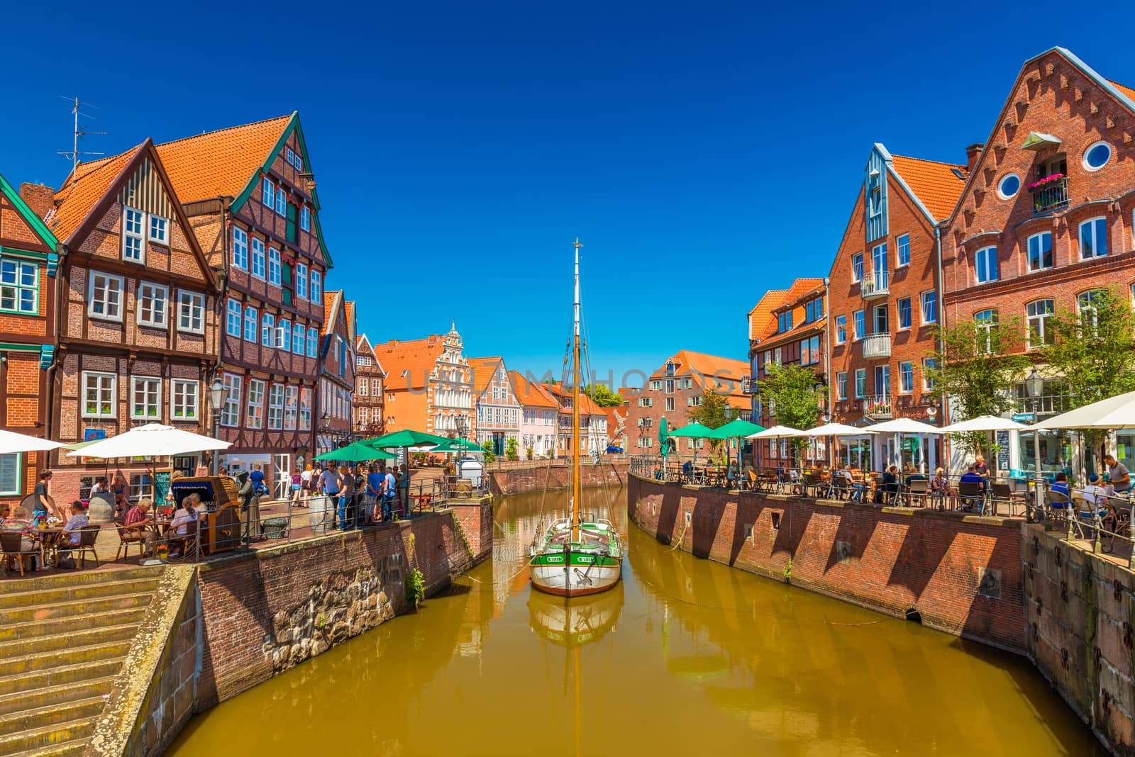 Stade - July 2019, Germany: View of a small German town with traditional architecture, canal with old wooden ship and clear blue sky