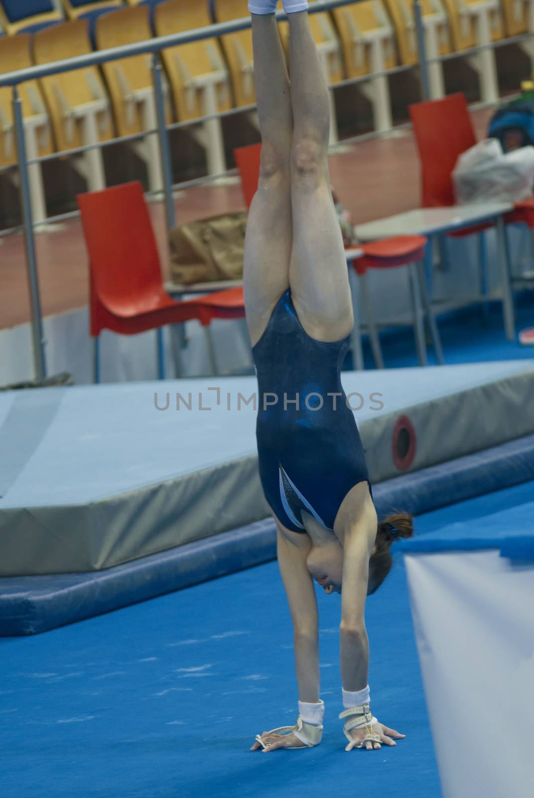 Athletic girl gymnast doing a handstand at the stadium, close up