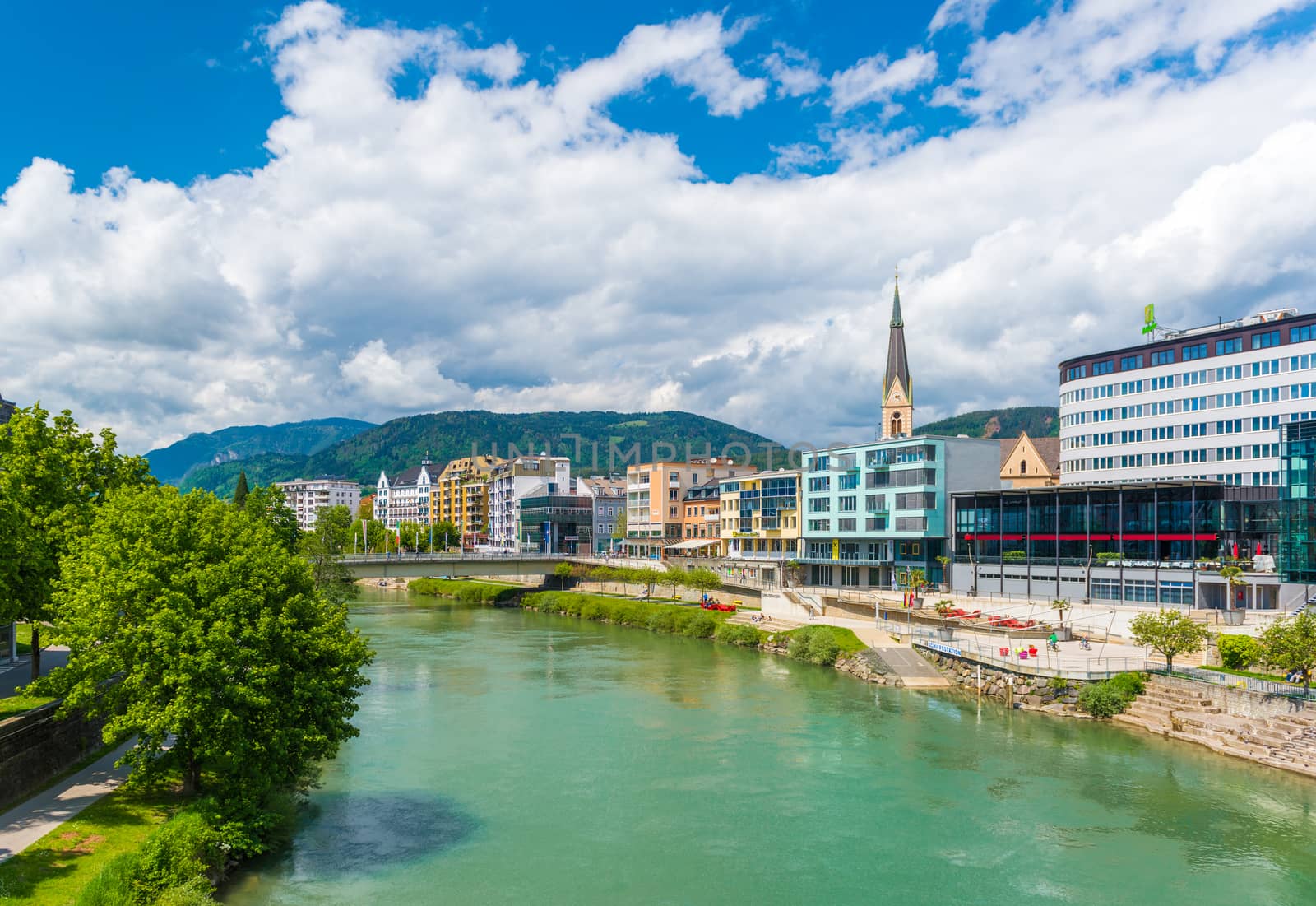 Villach - May 2016, Austria: Cityscape of the small Austrian city of Villach on a sunny day, view of Drava river, historical buildings, hotels and Church in the old city centera