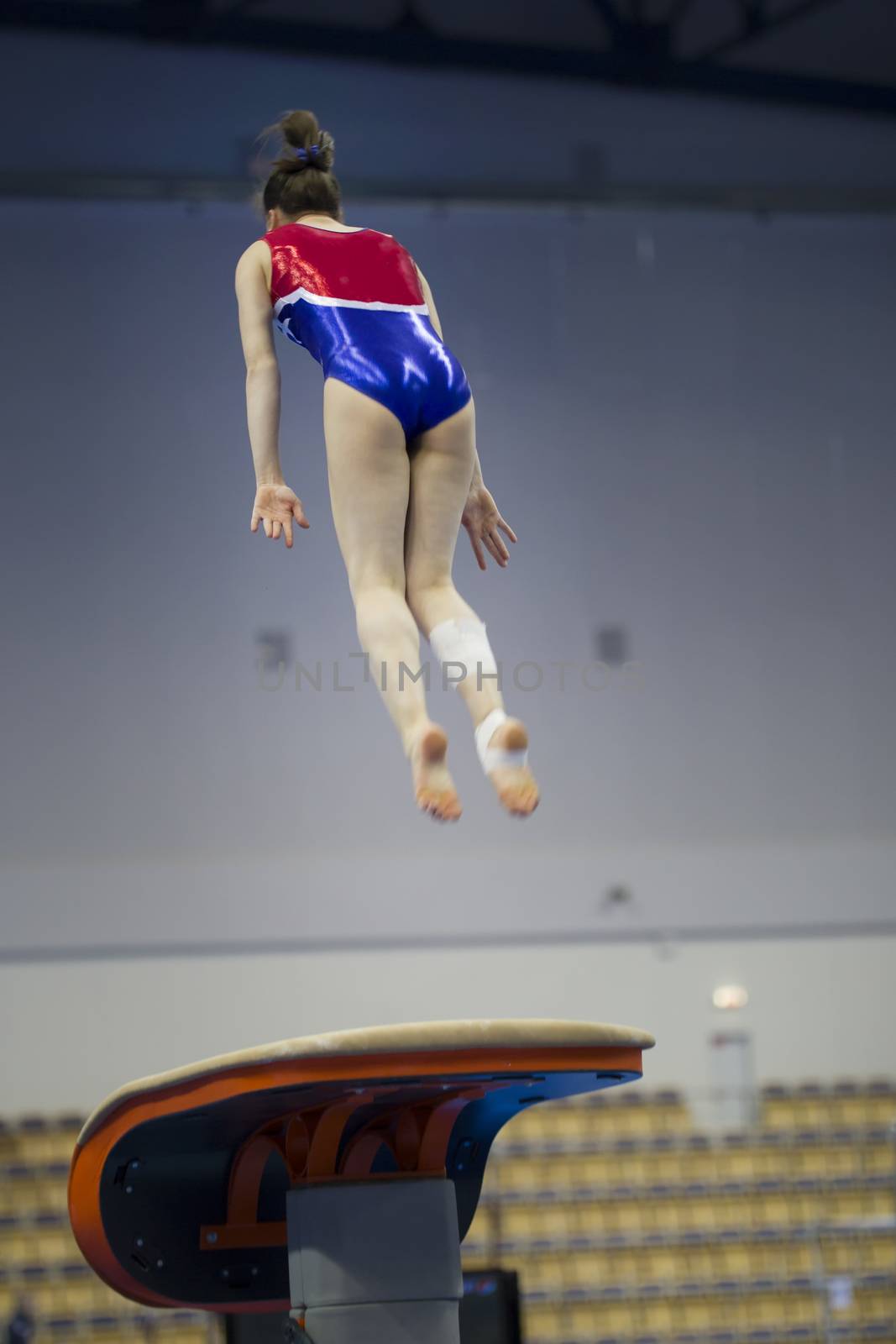 Female athlete gymnast performing a leap at the championship by Studia72