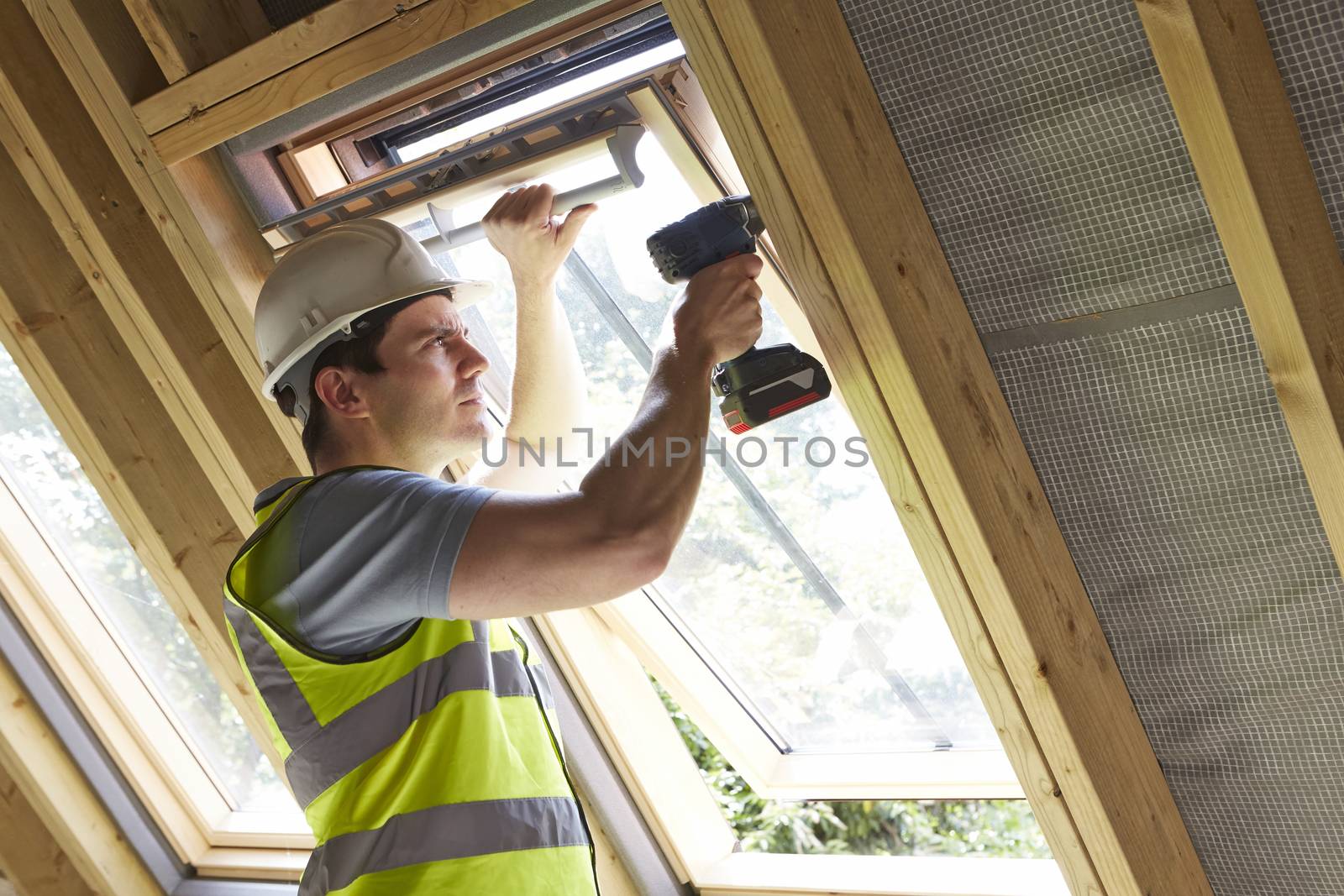 Construction Worker Using Drill To Install Window