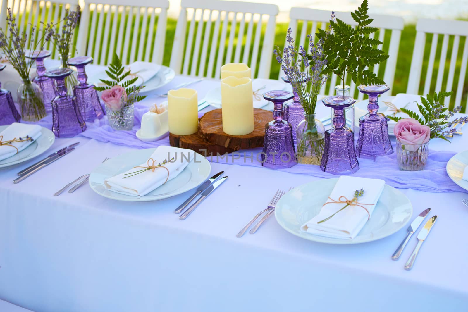 Elegant table setting for wedding engagement Easter dinner with white ceramic plates cotton napkin tied with twine lavender flowers candles. Provence style.