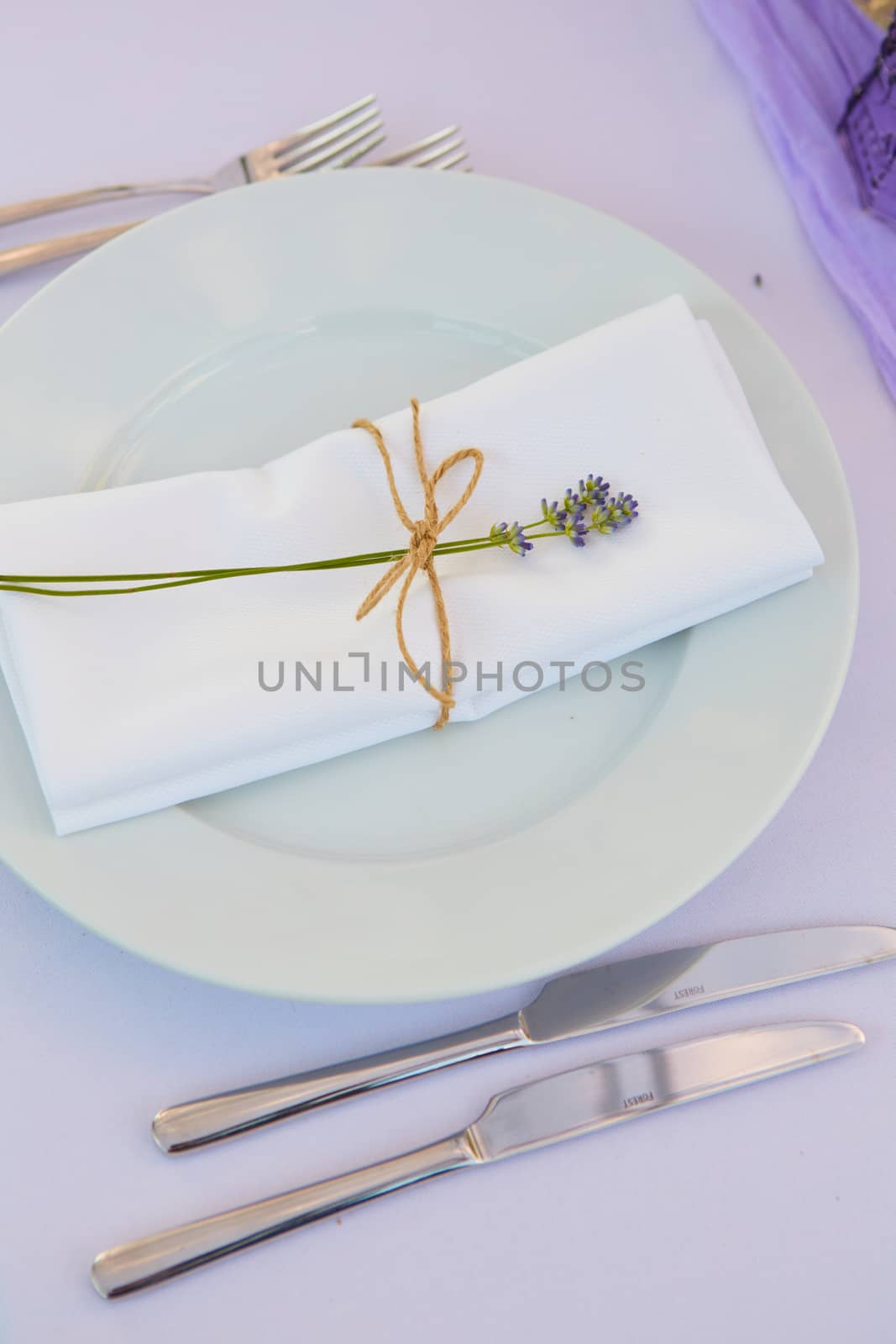 Elegant table setting for wedding engagement Easter dinner with white ceramic plates cotton napkin tied with twine lavender flowers candles. Provence style by sarymsakov
