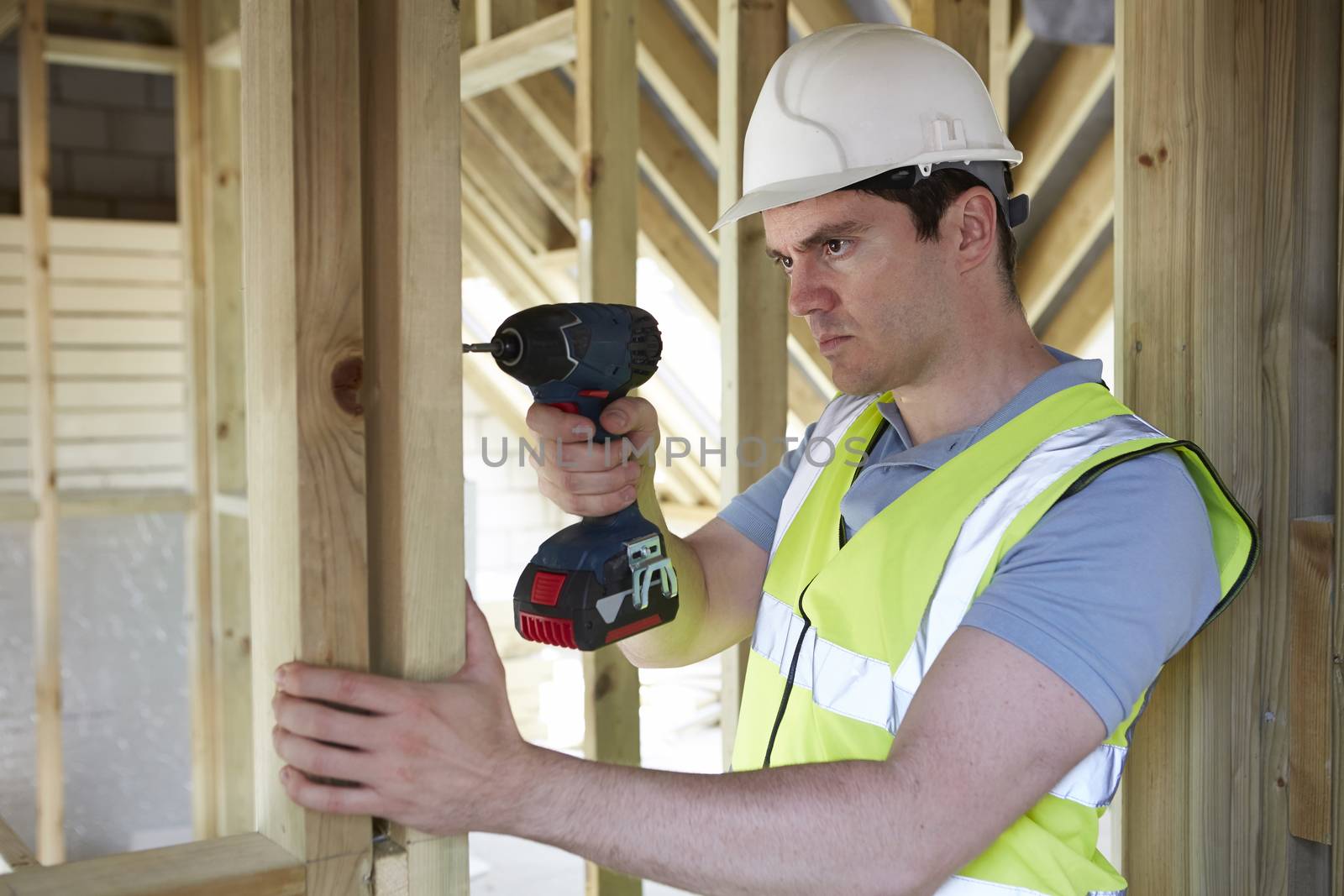 Construction Worker Using Cordless Drill On House Build