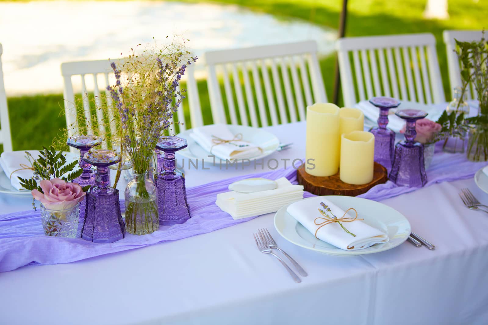 Elegant table setting for wedding engagement Easter dinner with white ceramic plates cotton napkin tied with twine lavender flowers candles. Provence style.