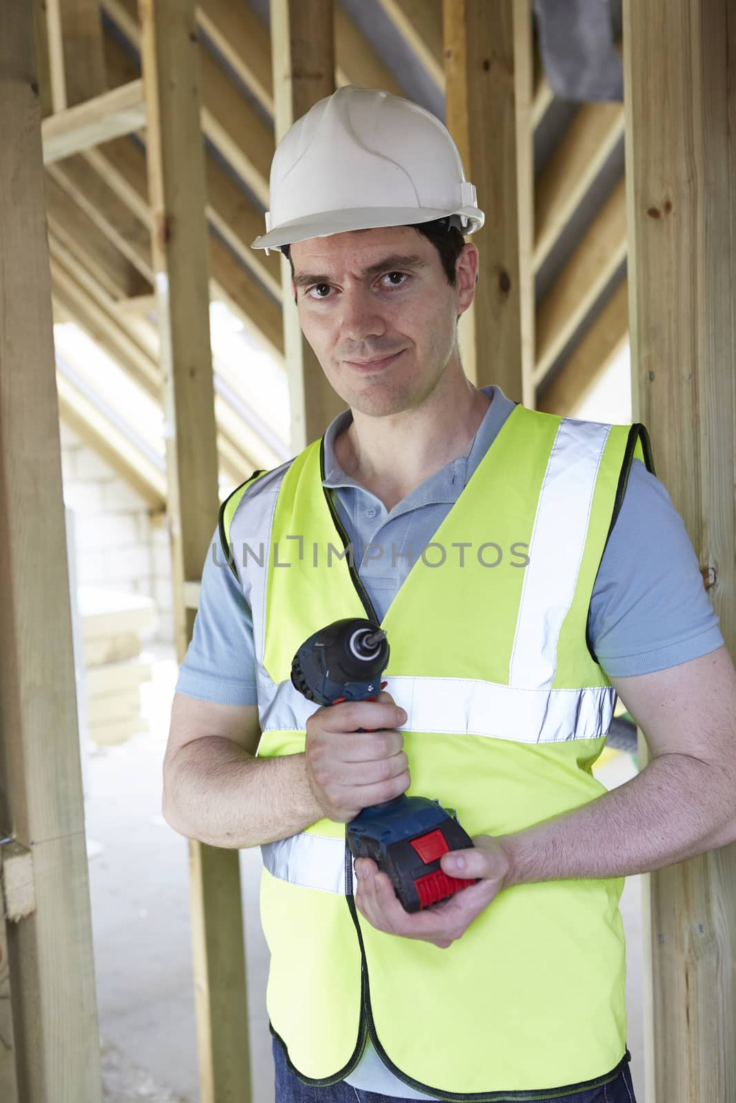 Builder On Construction Site Holding Cordless Drill