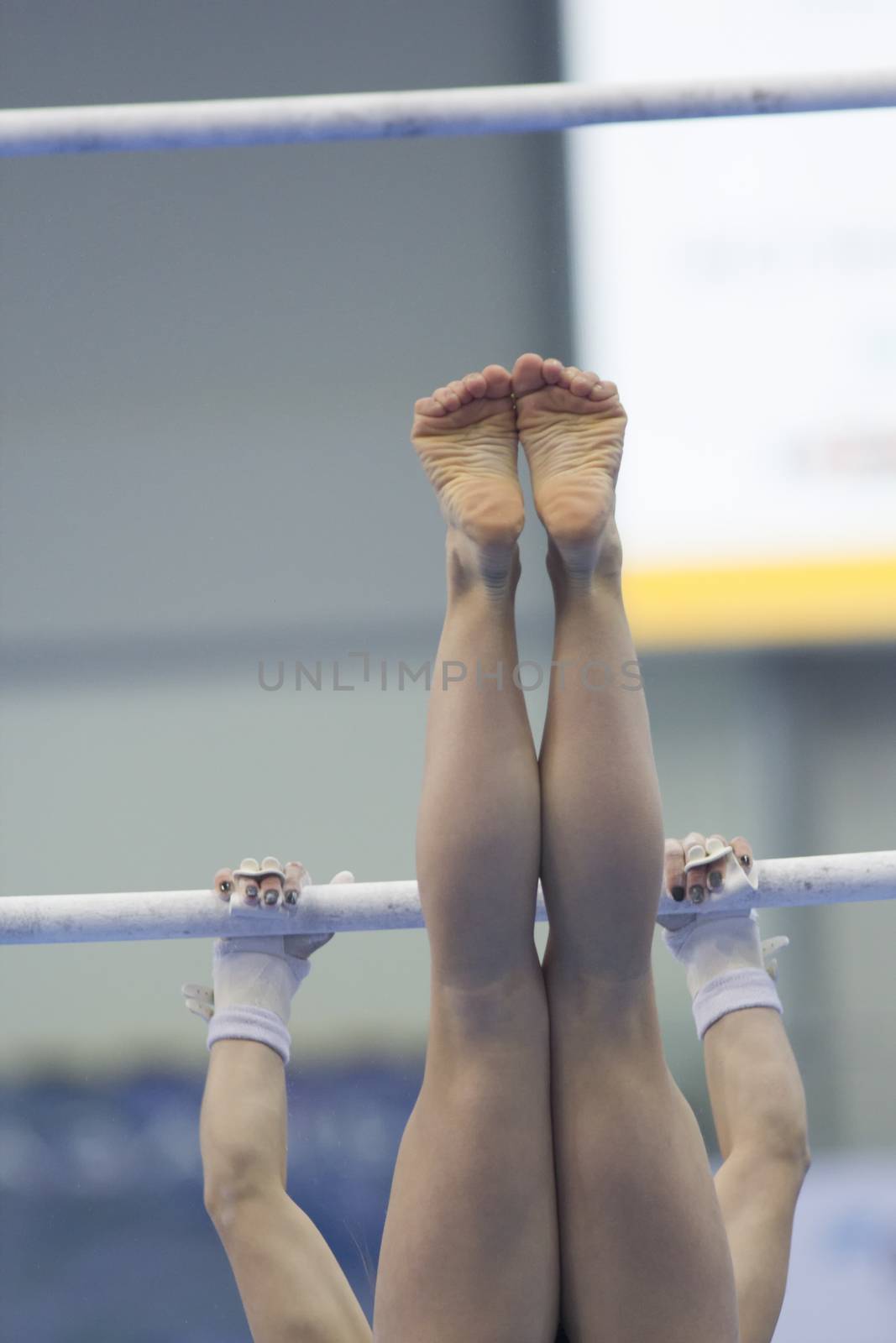 Legs hanging on the crossbar of the athletic woman, close up