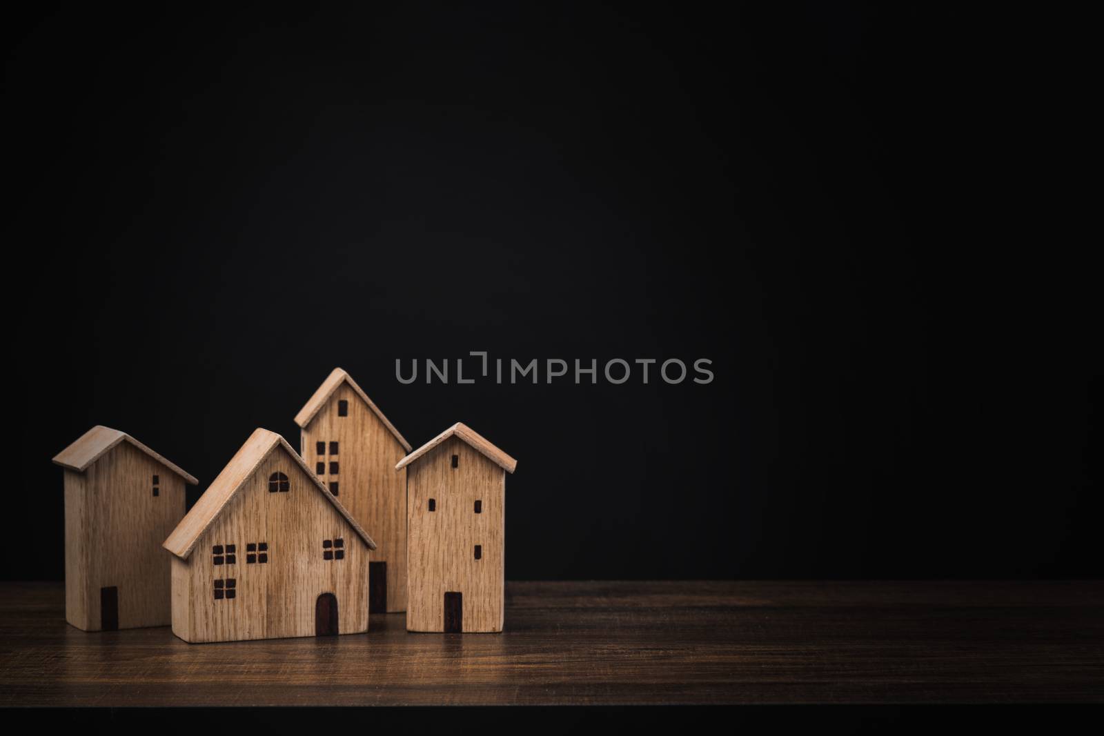 real estate concept, small wooden house or home on table with black background 