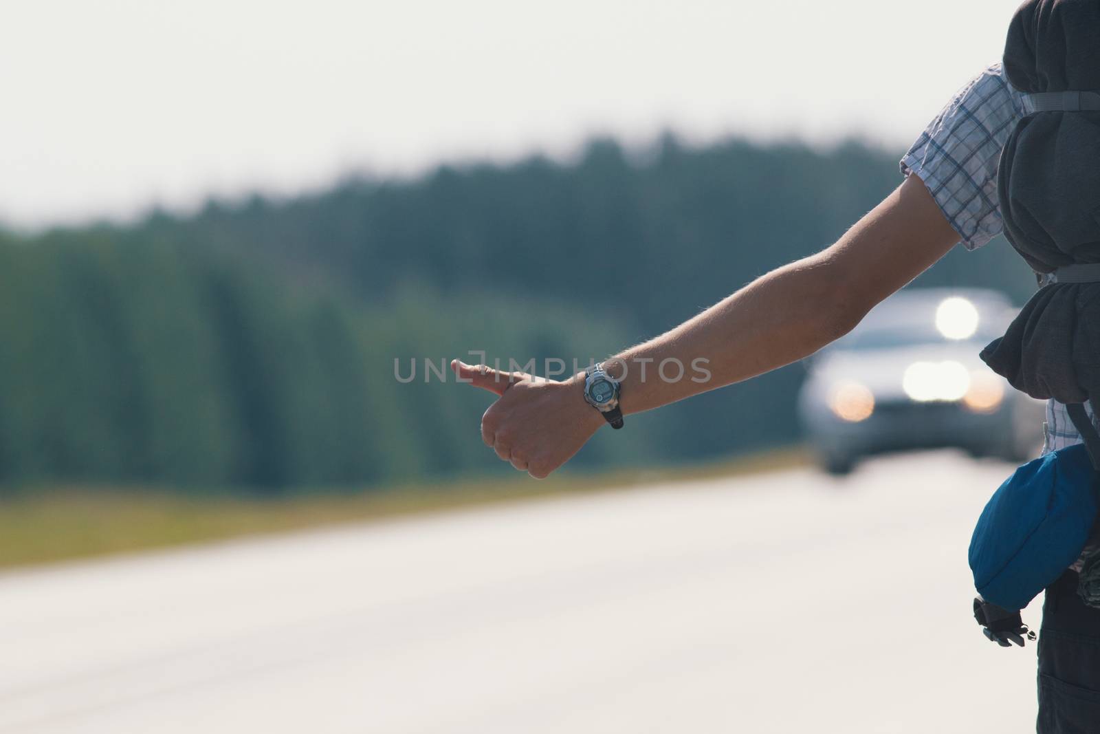 Hand of a young guy who honks on the road, hitchhiking, close up