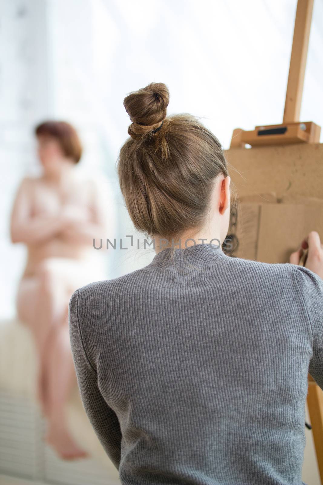Back of female painter draws on the easel nude woman , close up