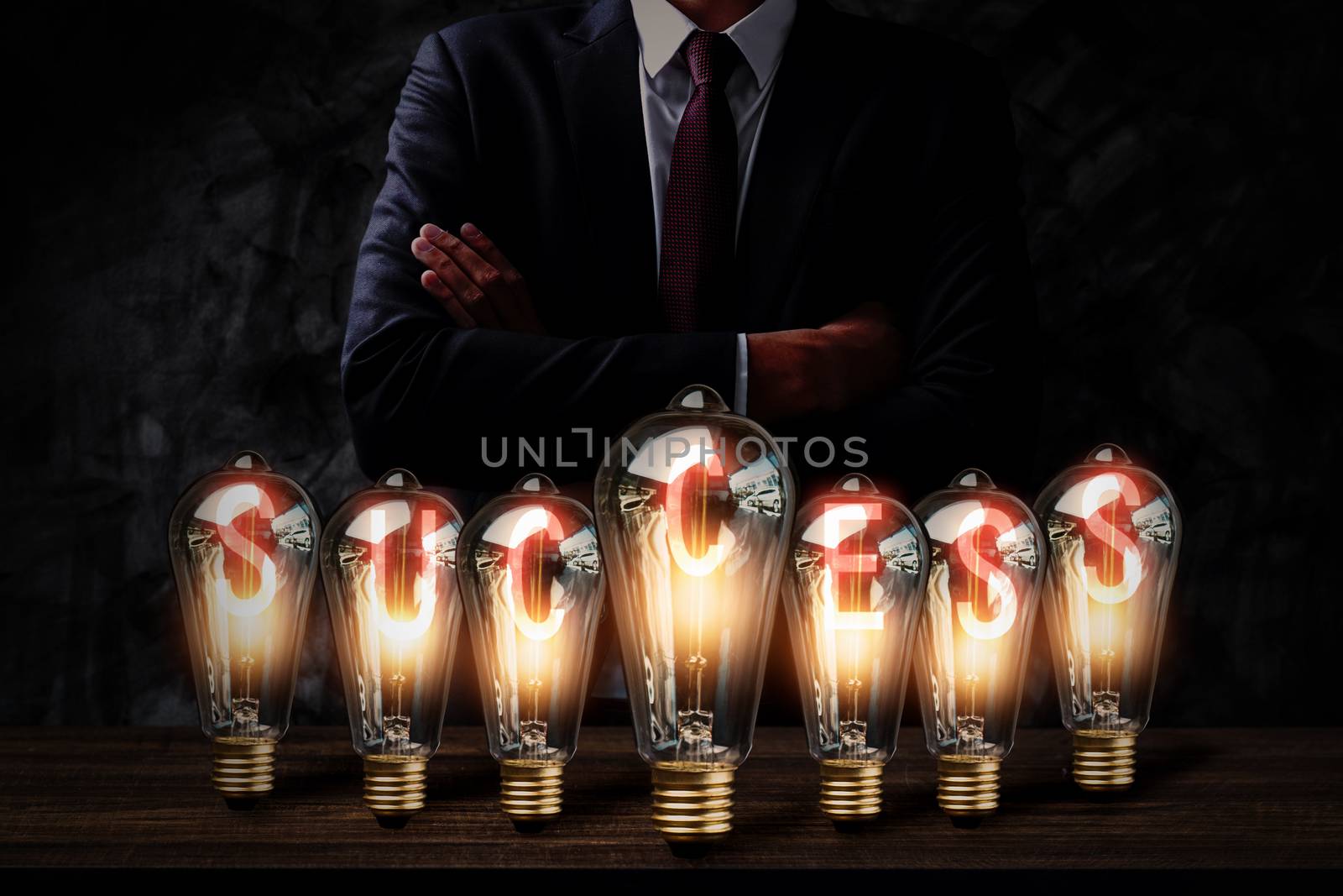 success and business innovation idea energy with light bulb on wood table and businessman in dark tone, successful creative leader and invention concept