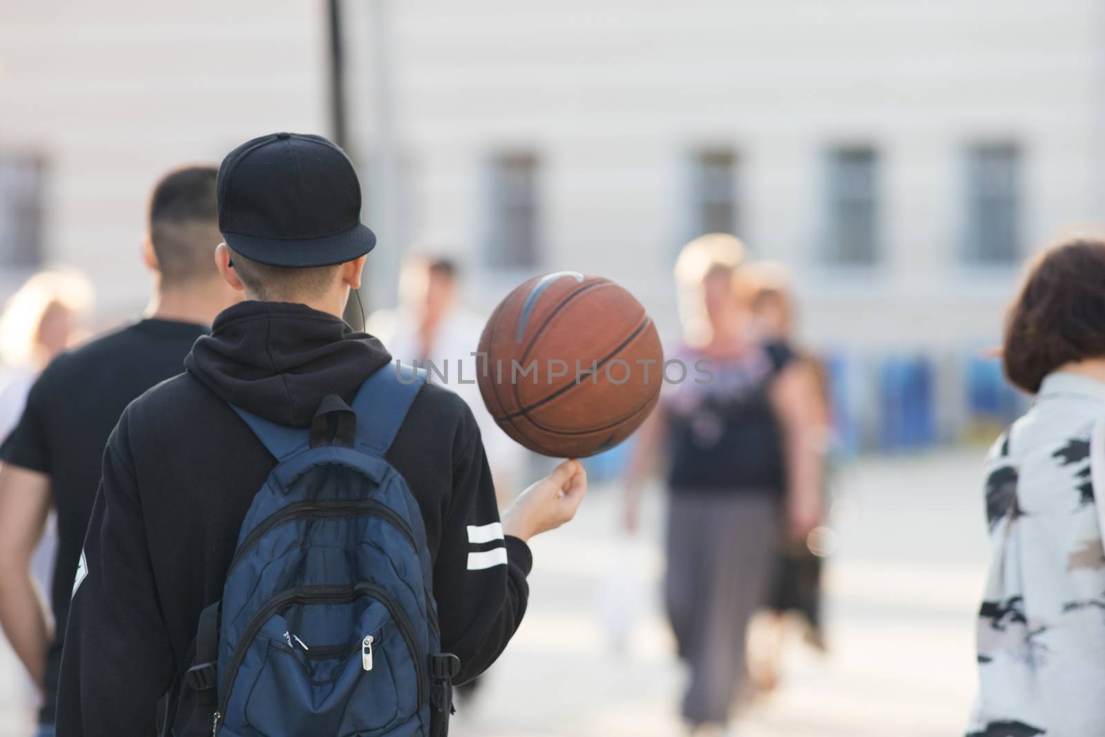 Young basketball player walking down the street with the ball, photo of the back