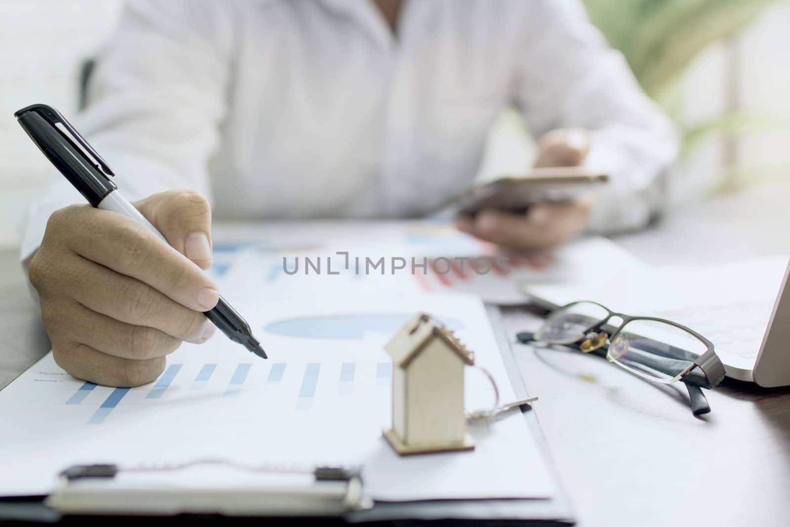 business man or banker checking profit finance graph of real estate and selling house on table 