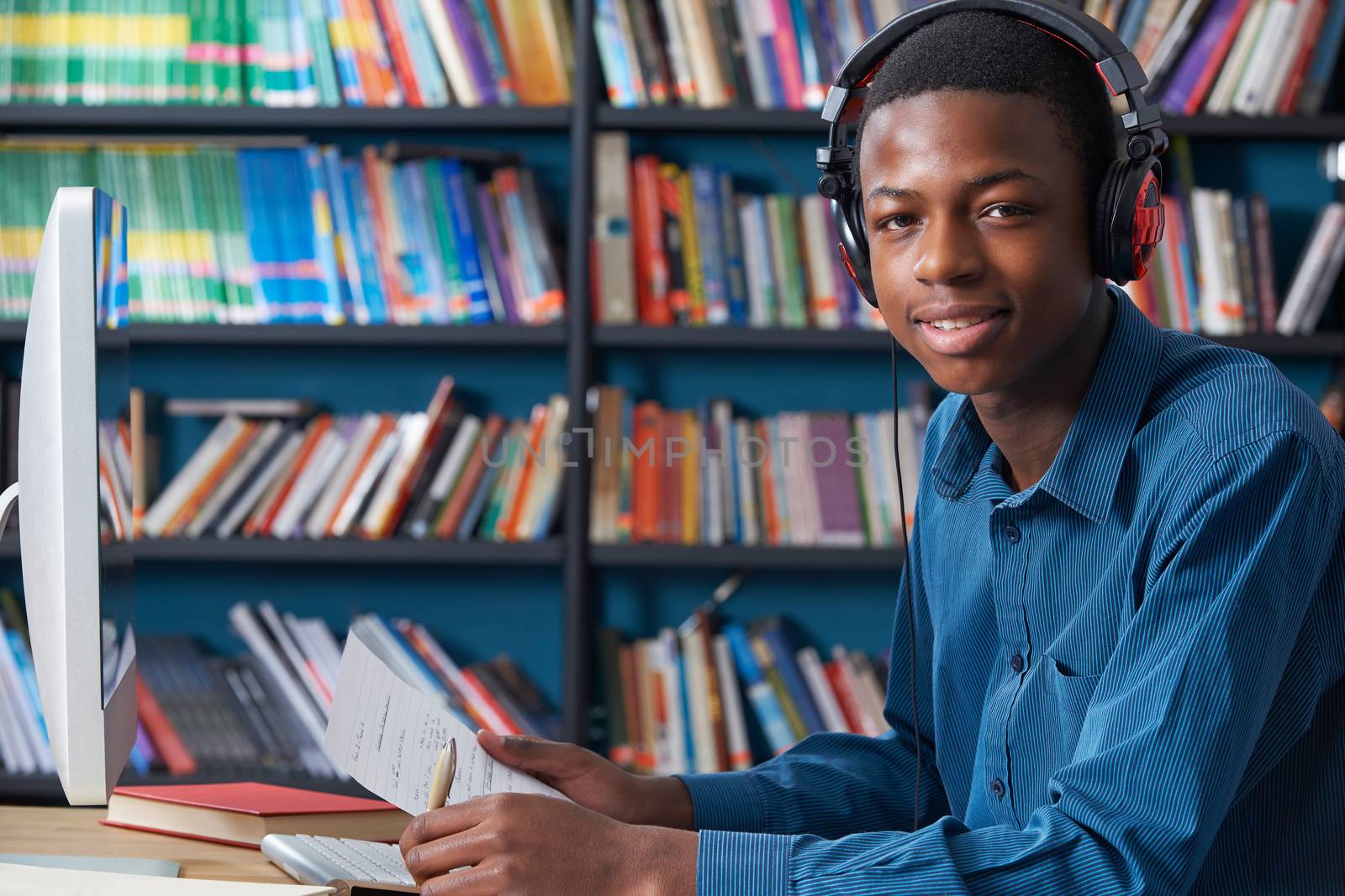 Male Teenage Student Working At Computer Wearing Headphones