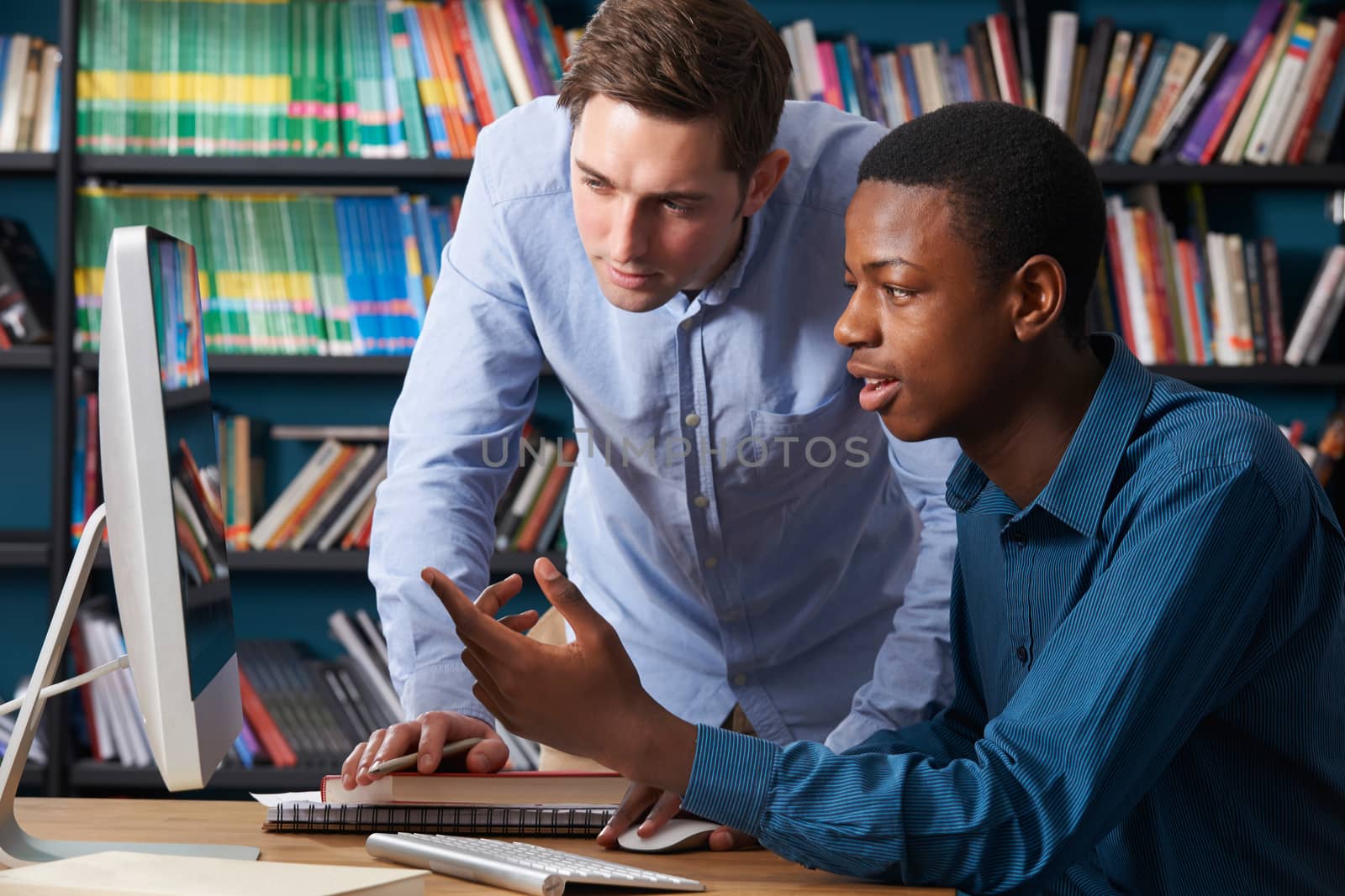 Teacher Working With Male Teenage Pupil At Computer by HWS