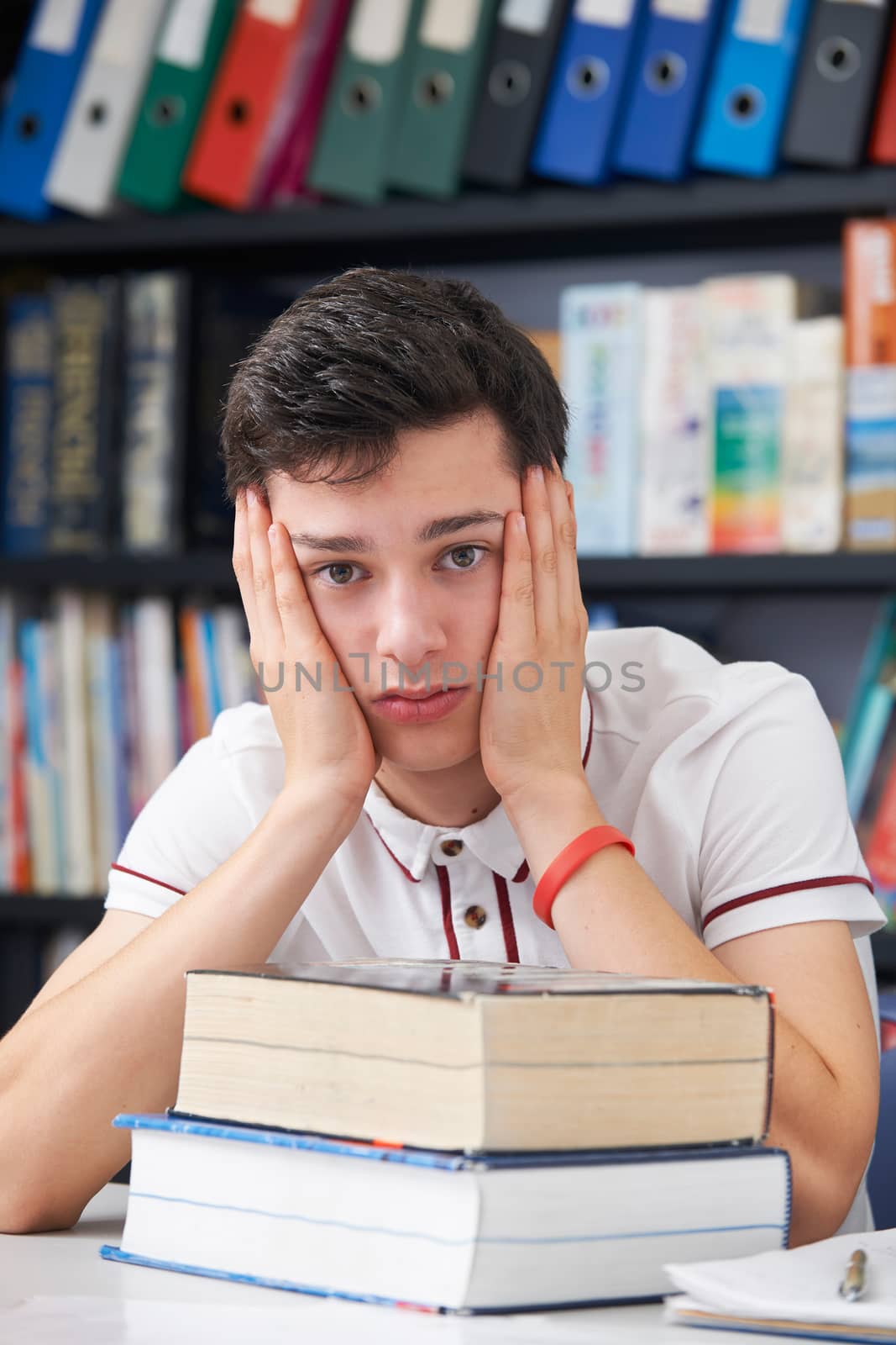 Stressed Male Pupil Working In Library by HWS