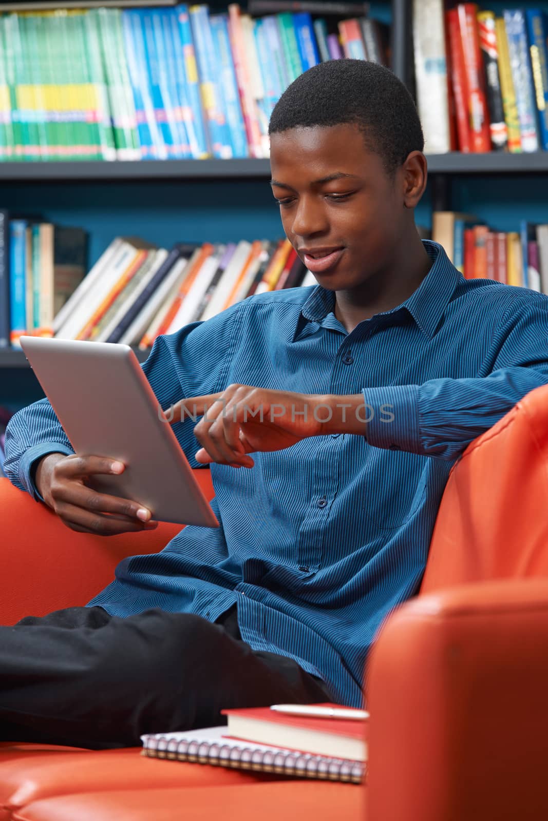Male Teenage Student Using Digital Tablet In Library