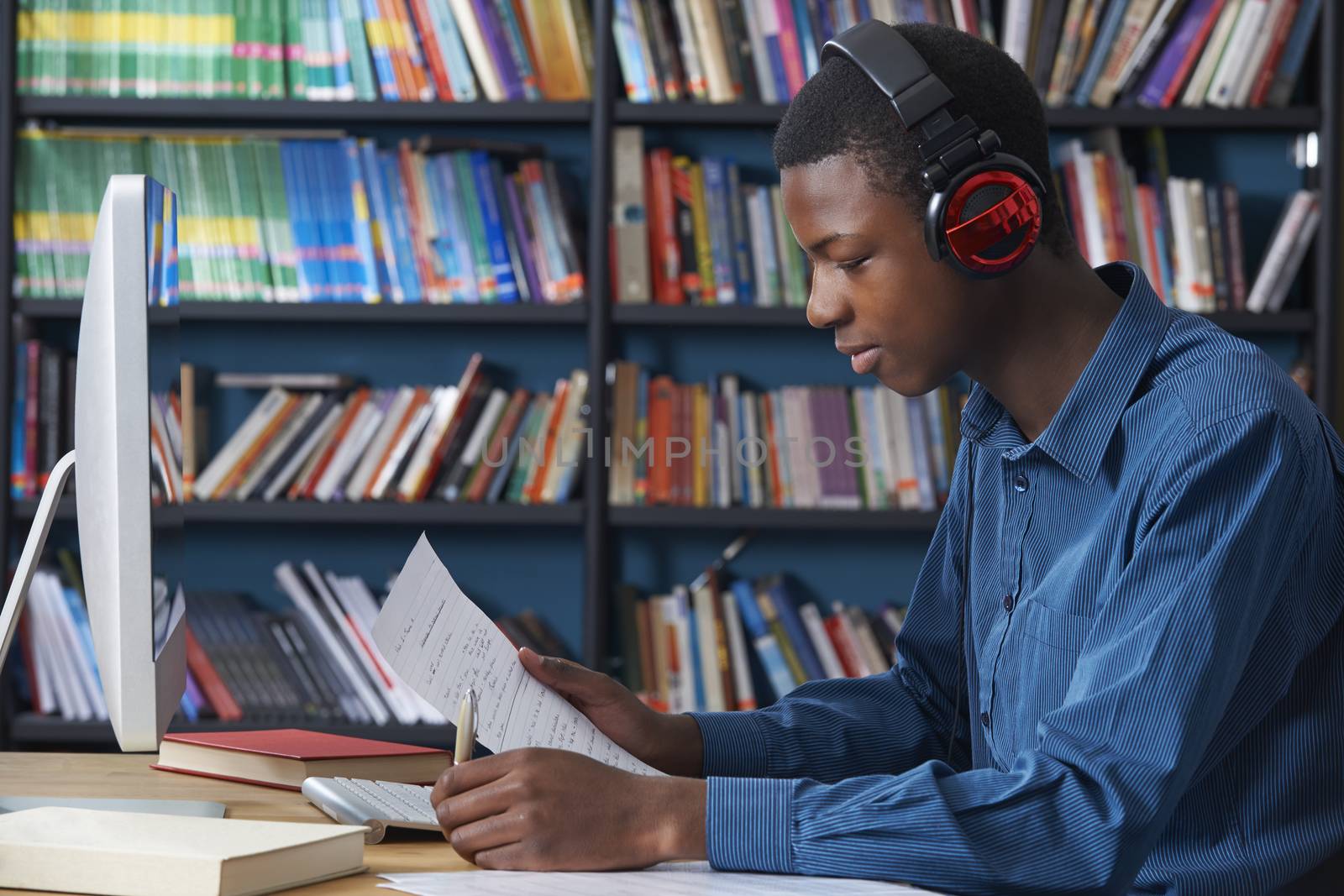 Male Teenage Student Working At Computer Wearing Headphones