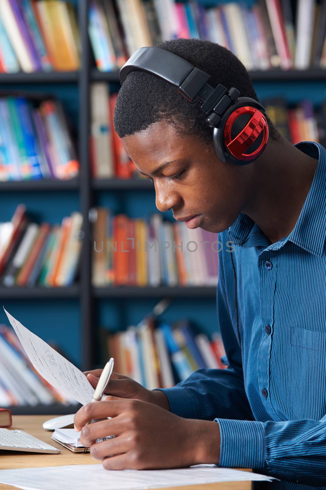 Male Teenage Student Working At Computer Wearing Headphones by HWS