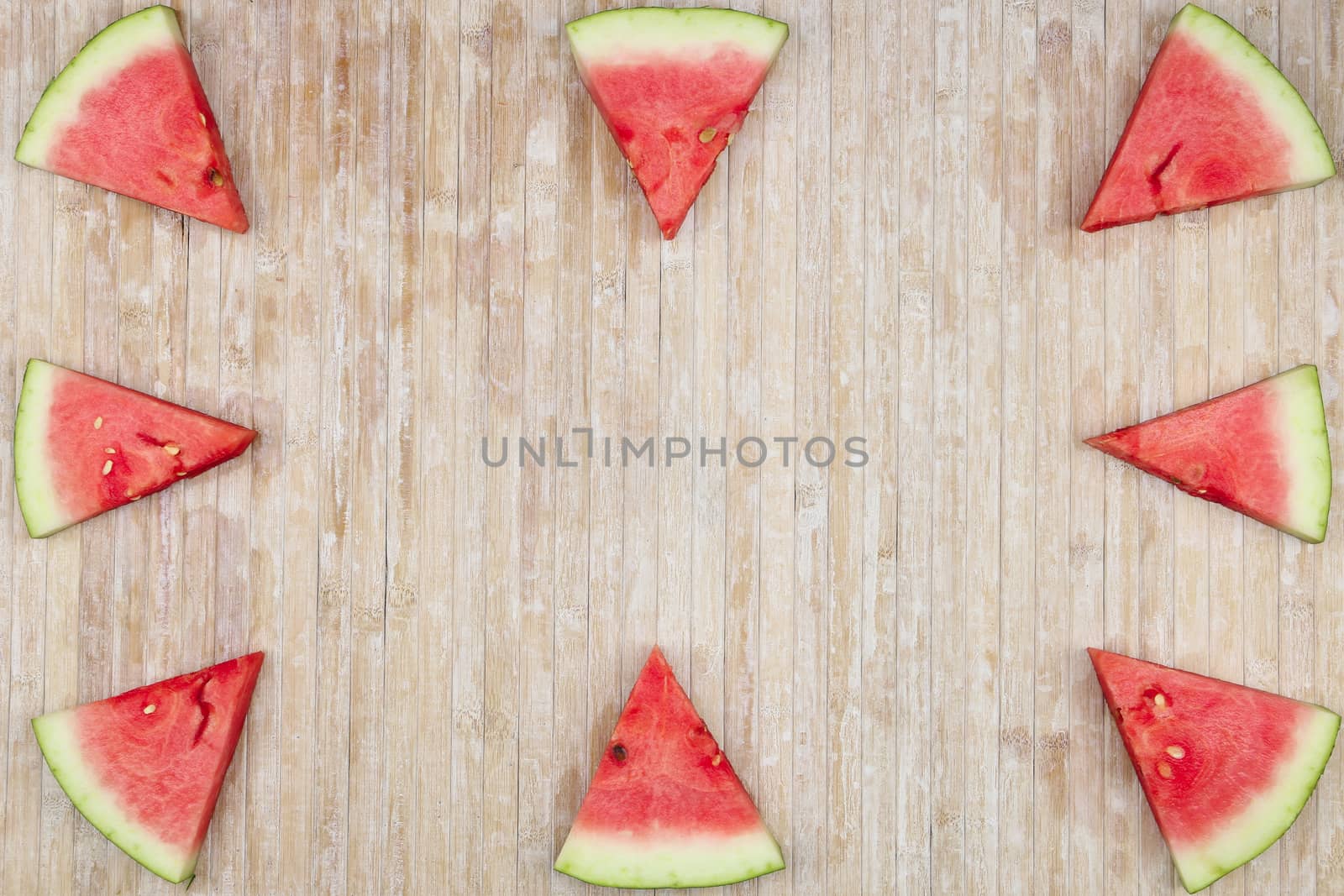 Triangular slices of watermelon that form geometric games for copy space on a light wooden background by robbyfontanesi