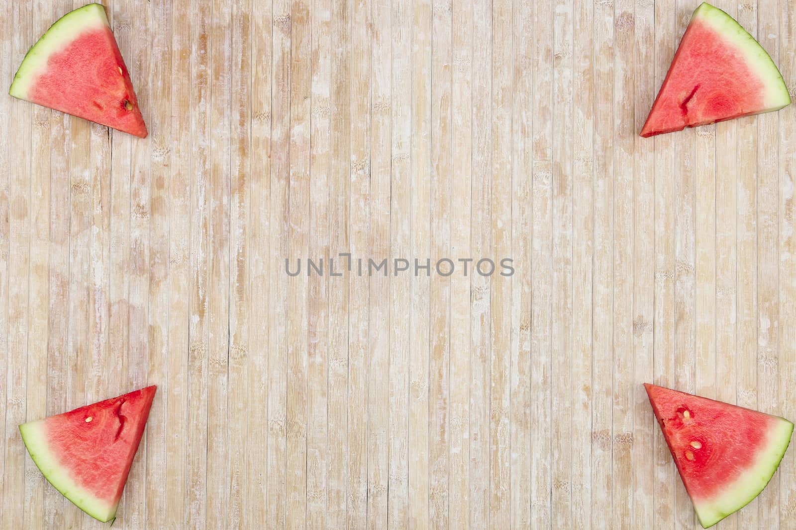 Triangular slices of watermelon that form geometric games for copy space on a light wooden background