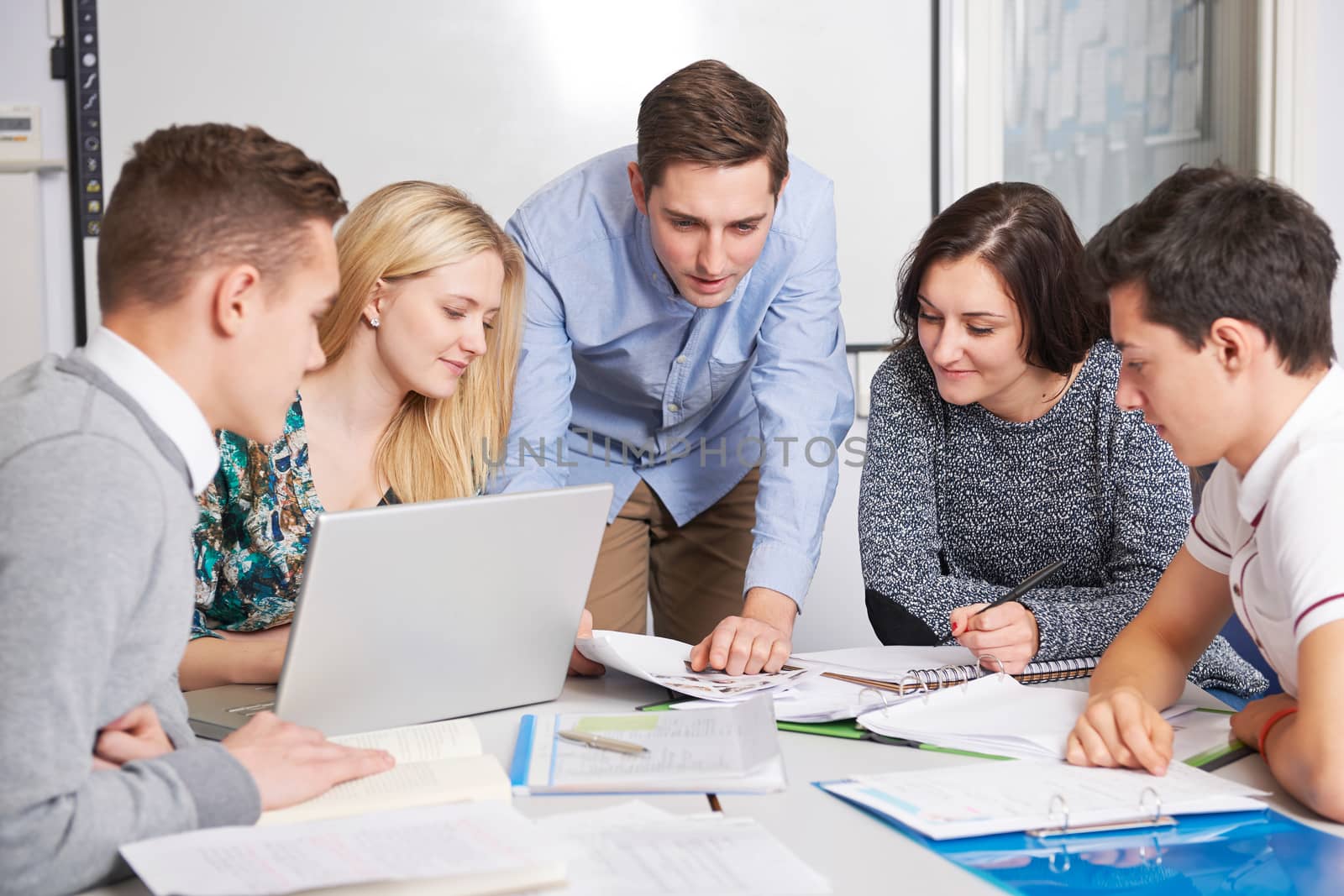 Teacher Working In Classroom With Students