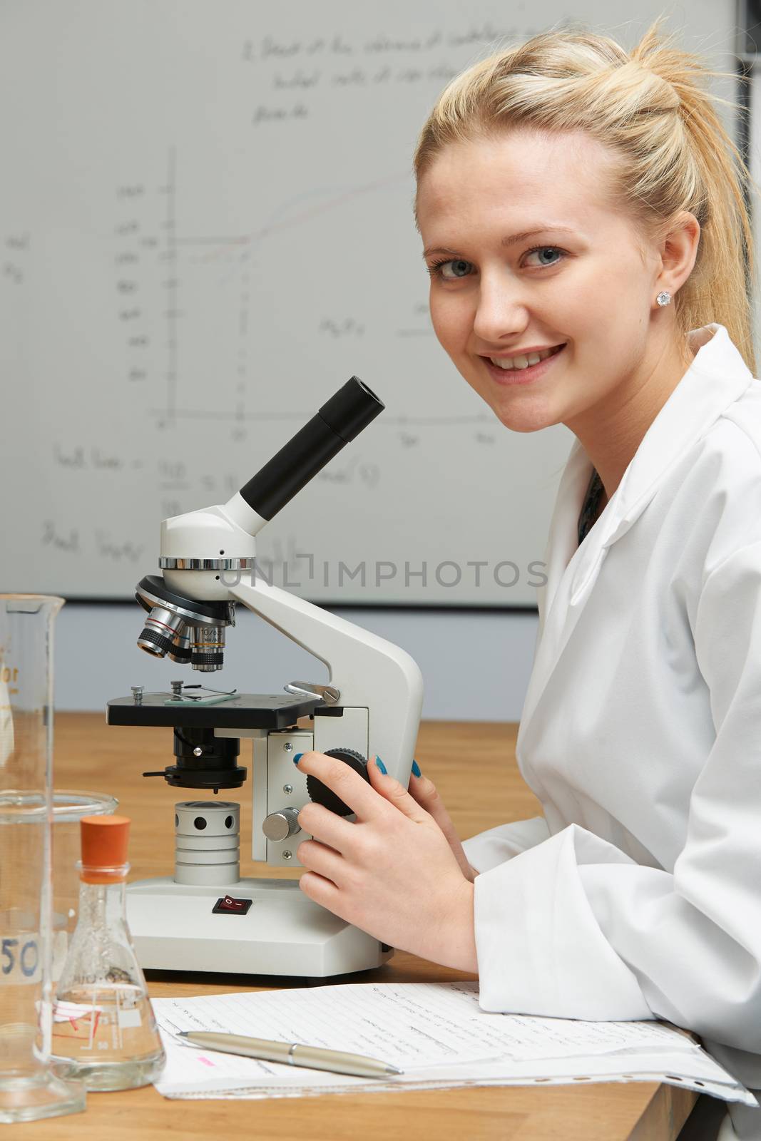 Female Pupil Using Microscope In Science Lesson by HWS