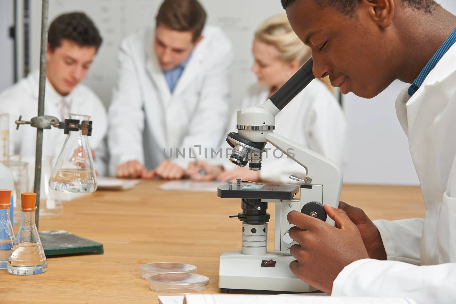 Male Pupil Using Microscope In Science Class by HWS