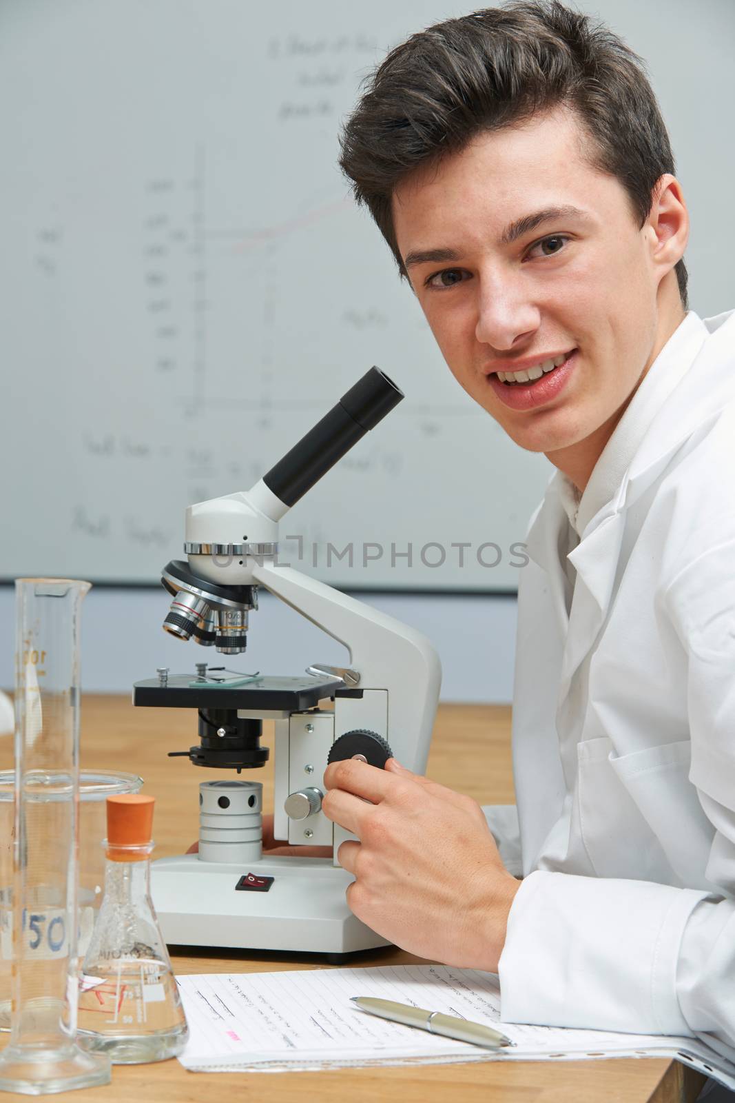 Portrait Of Male Pupil Using Microscope In Science Laboratory by HWS