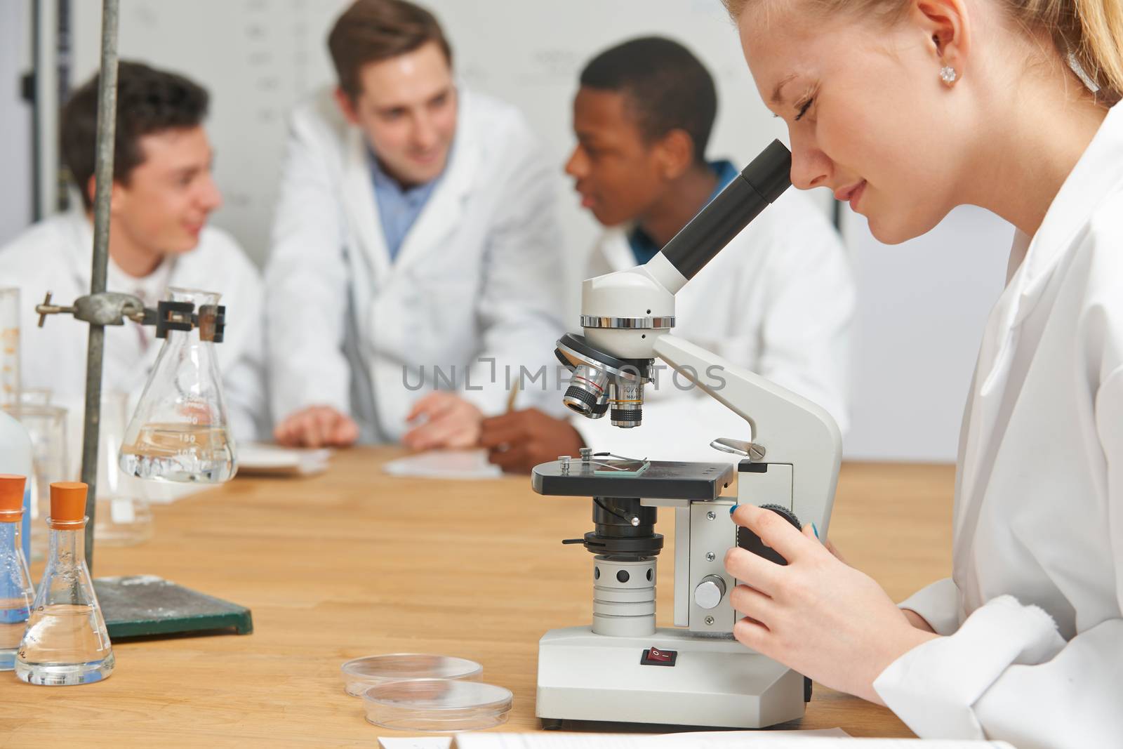 Female Pupil Using Microscope In Science Lesson