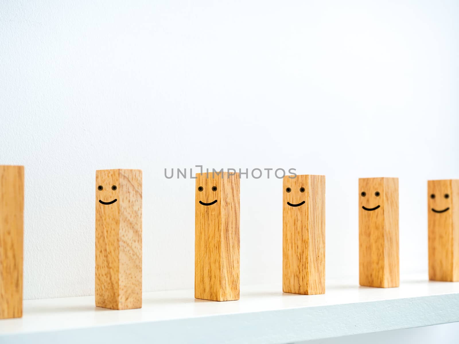 Social Distancing concept. Row of smiley face wooden dominoes with distance space on shelf on white background.
