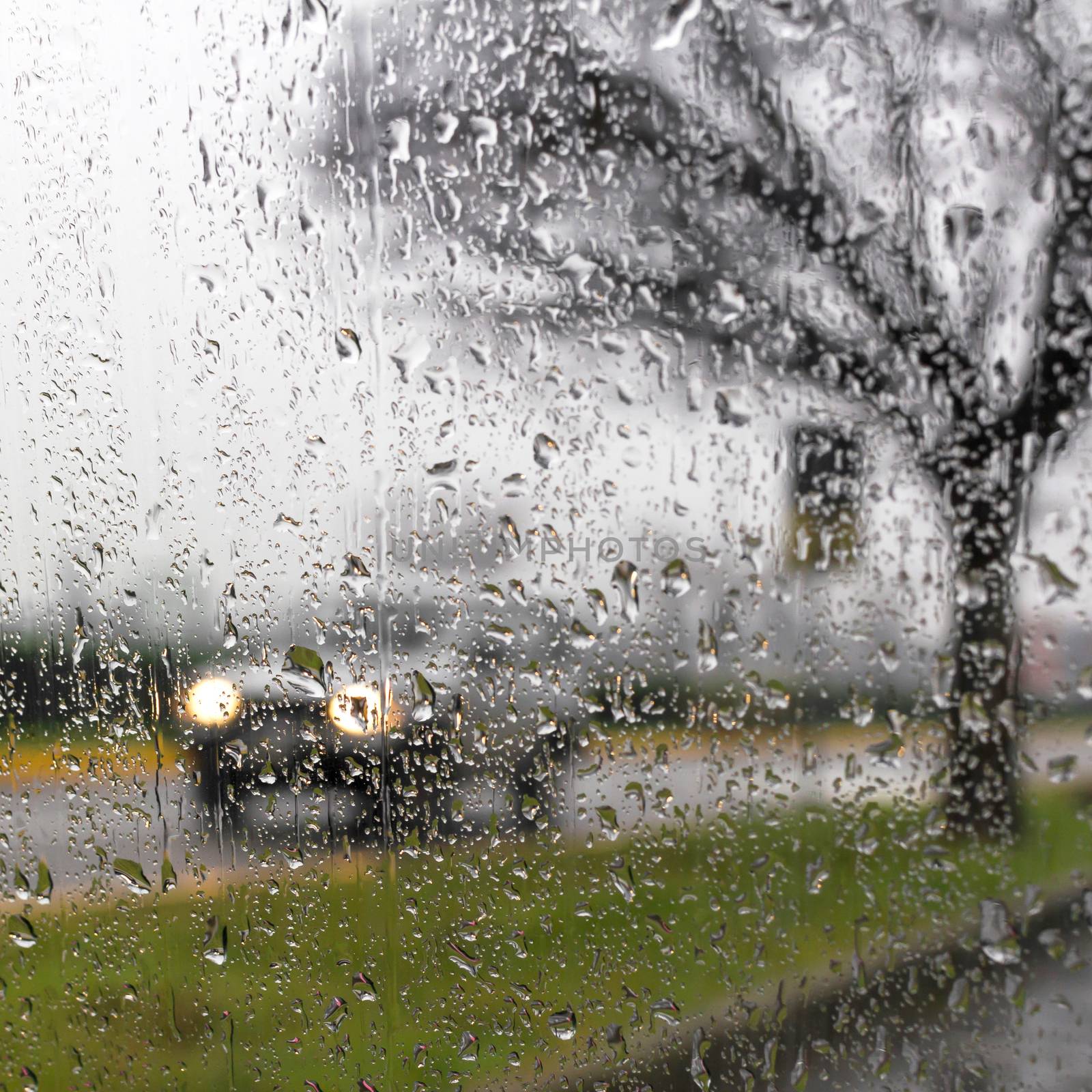 Rain on the car glass, wet day, shot through a windscreen, focusing on the rain droplets.