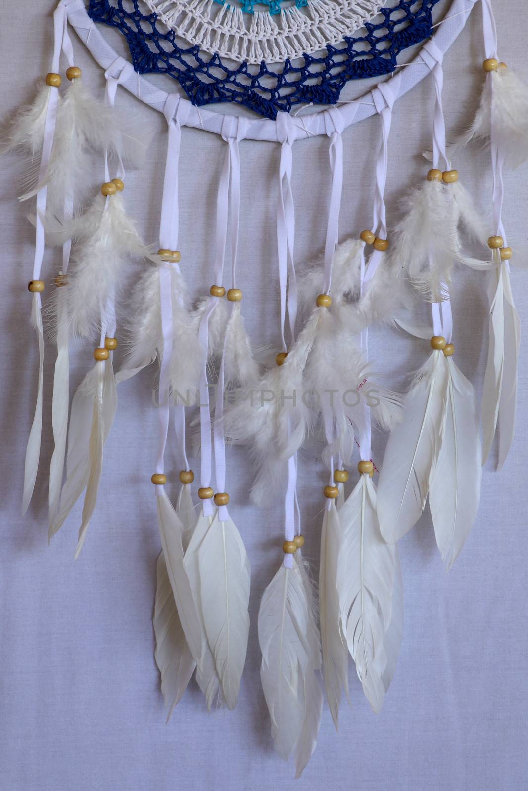 Closeup of white dream catcher a small white hoop decorated with feathers and beads.