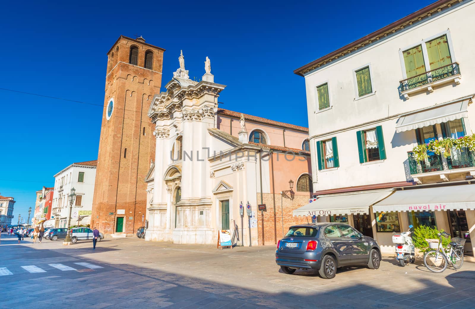 Chioggia - September 2016, Veneto, Italy: Street view of Chioggia, Saint Andrea Church (Chiesa di Sant'Andrea), residential houses, shops, car and scooter parked near them