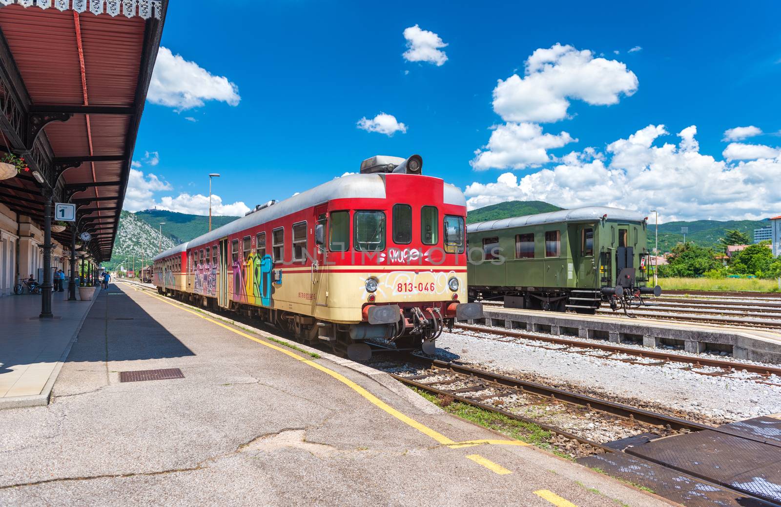 Nova Gorica (Gorizia) - June 2016, Slovenia: Wide angle view of trains on tracks at the old train station, view from the platform, summer day with blue sky and cumulus clouds