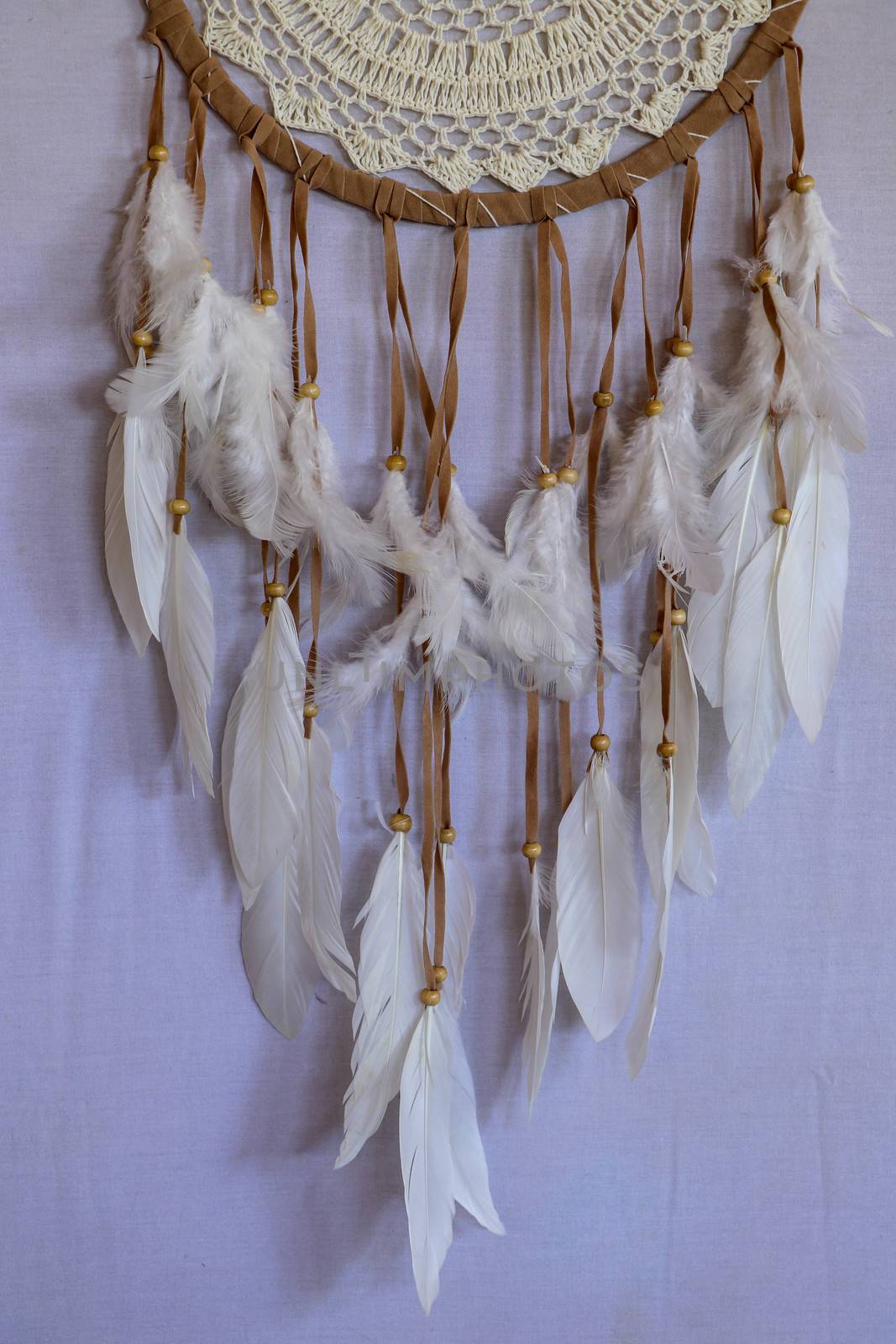 Closeup of white dream catcher a small white hoop decorated with feathers and beads.