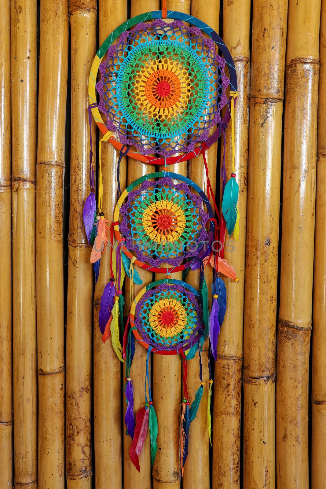 Beautiful multicolored handmade dreamcatcher on natural bamboo background.