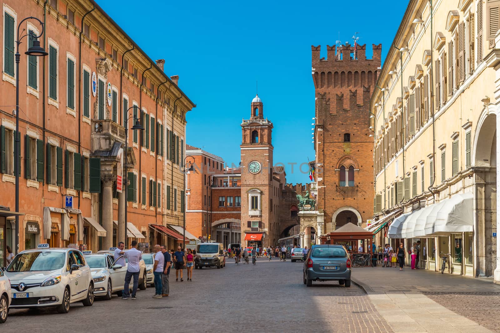Ferrara - July 2017, Emilia Romagna, Italy: Central street of Ferrara. Taxi cabs and drivers near them. People walking in the historical part of the city