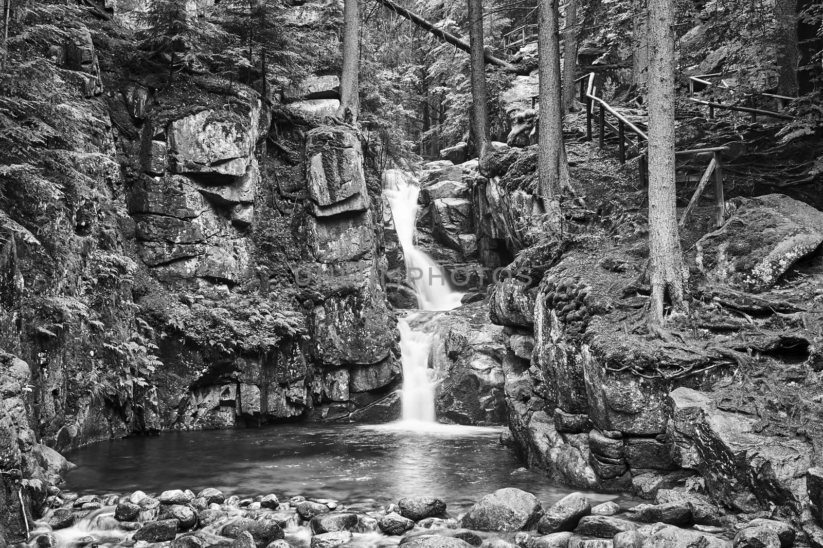 Rocks, boulders and waterfall in the forest in the Giant Mountains in Poland, black and white