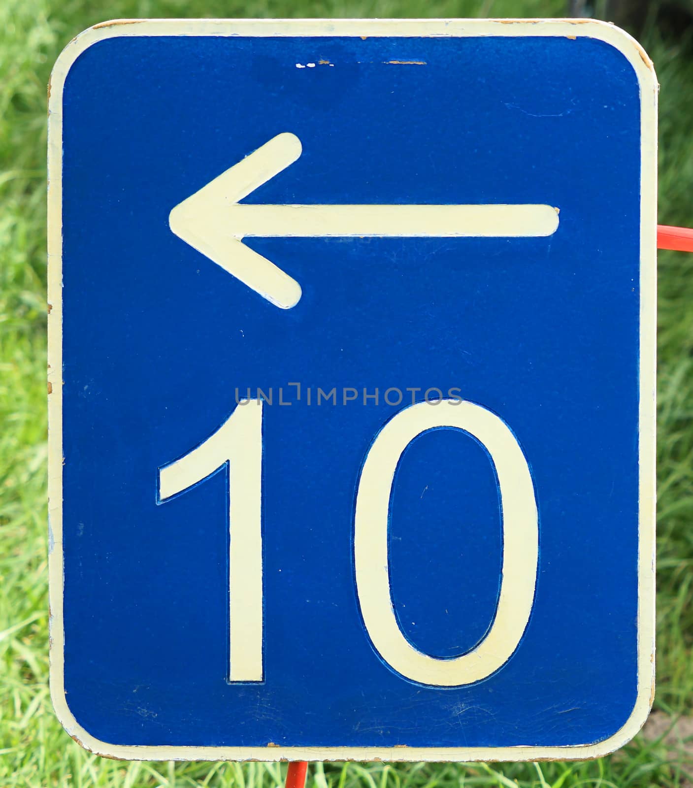 The number ten on a blue metal plate with a white arrow pointing to the left by geogif