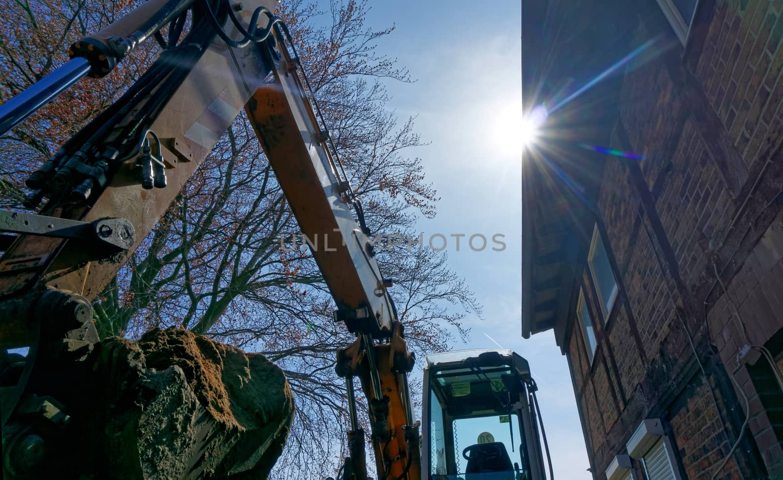 large excavator shovel in the backlight filled with a mighty load of loose brown sand at the construction site, germany