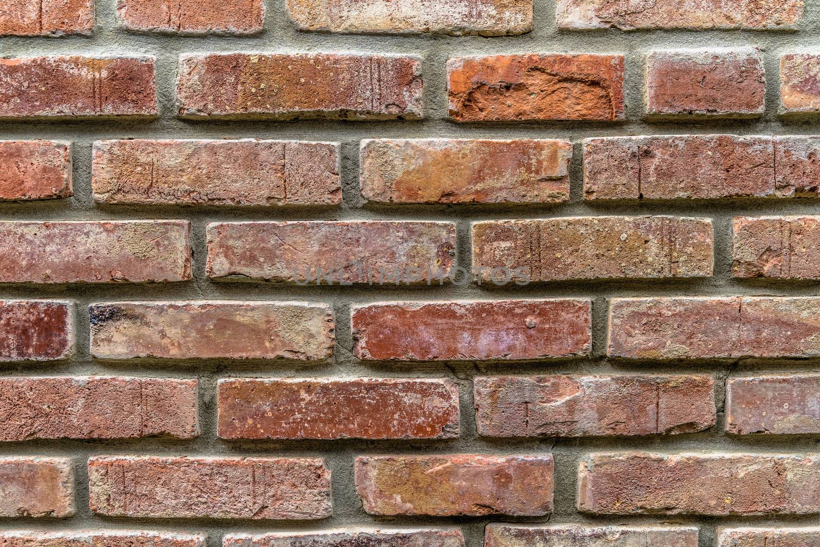 An old wall of restored bricks with a strongly faded red colour and uneven joints, germany
