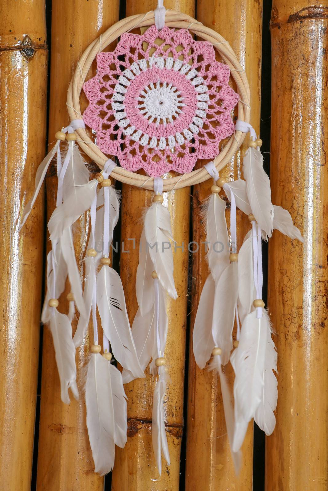 Pink ash crochet doily dream catcher close up on dark gray textured background. Texture of concrete, copy space for text. Wodden background.