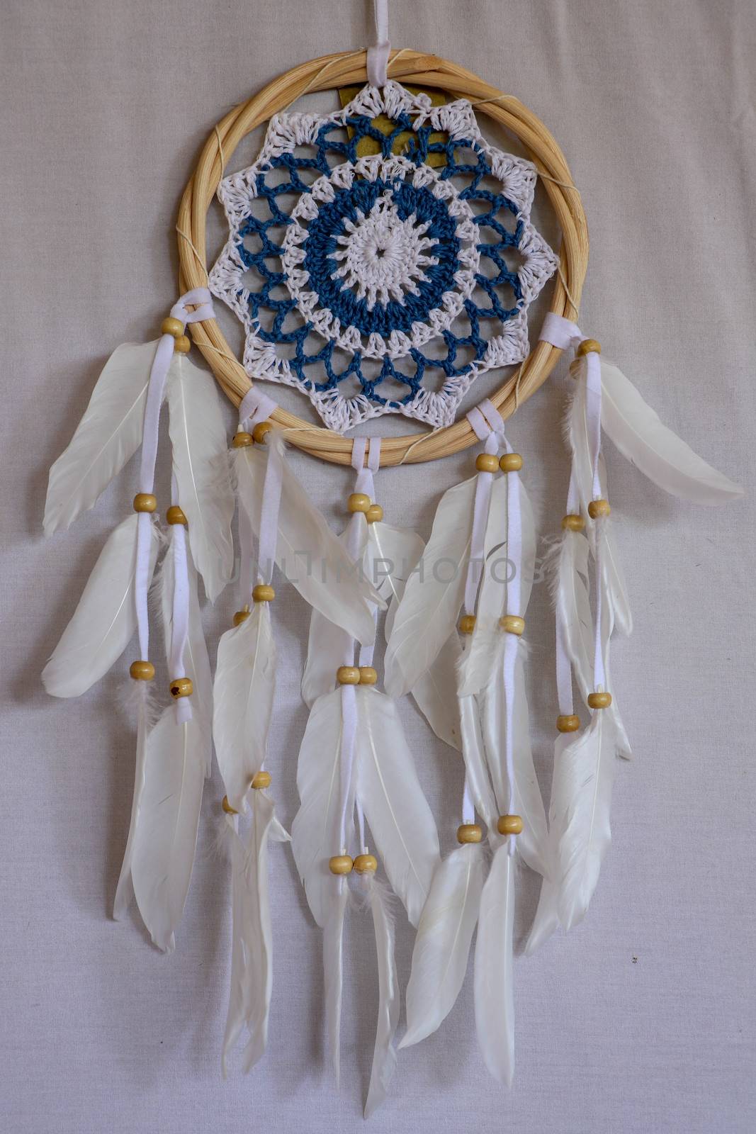Blue Dreamcatcher with feathers and beads isolated on a white background.