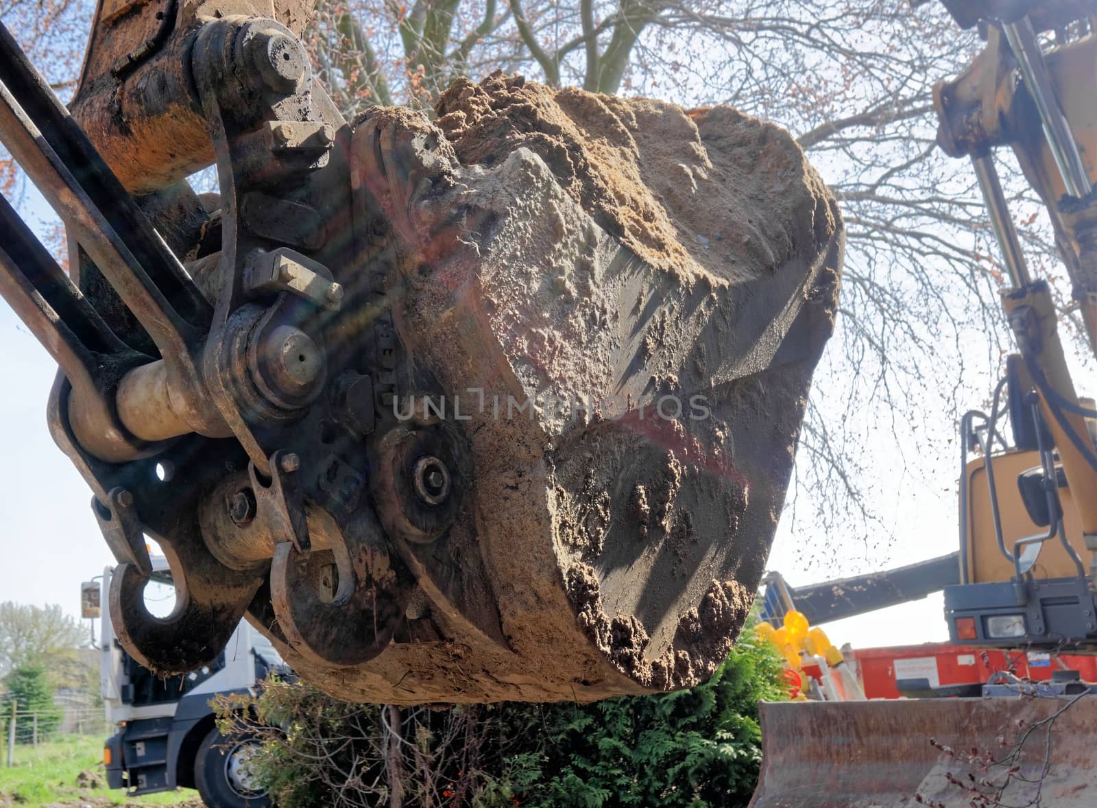 Close-up of a large excavator shovel filled with a mighty load of loose brown sand at the construction site by geogif