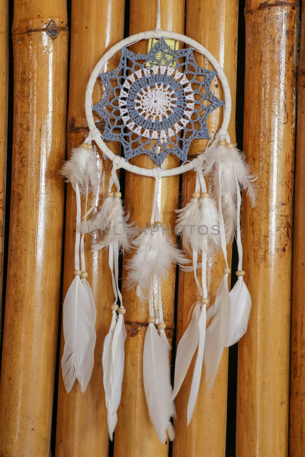 Blue Dreamcatcher with feathers and beads isolated on a wodden background.
