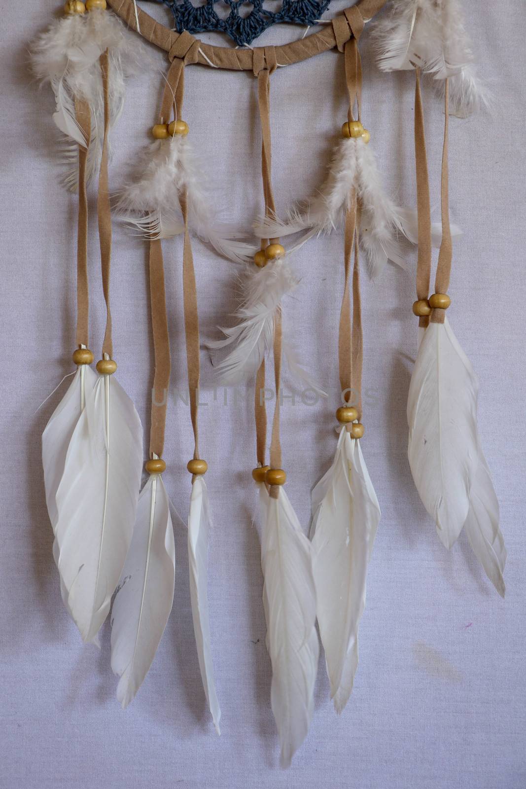 Closeup of white dream catcher a small white hoop decorated with feathers and beads.