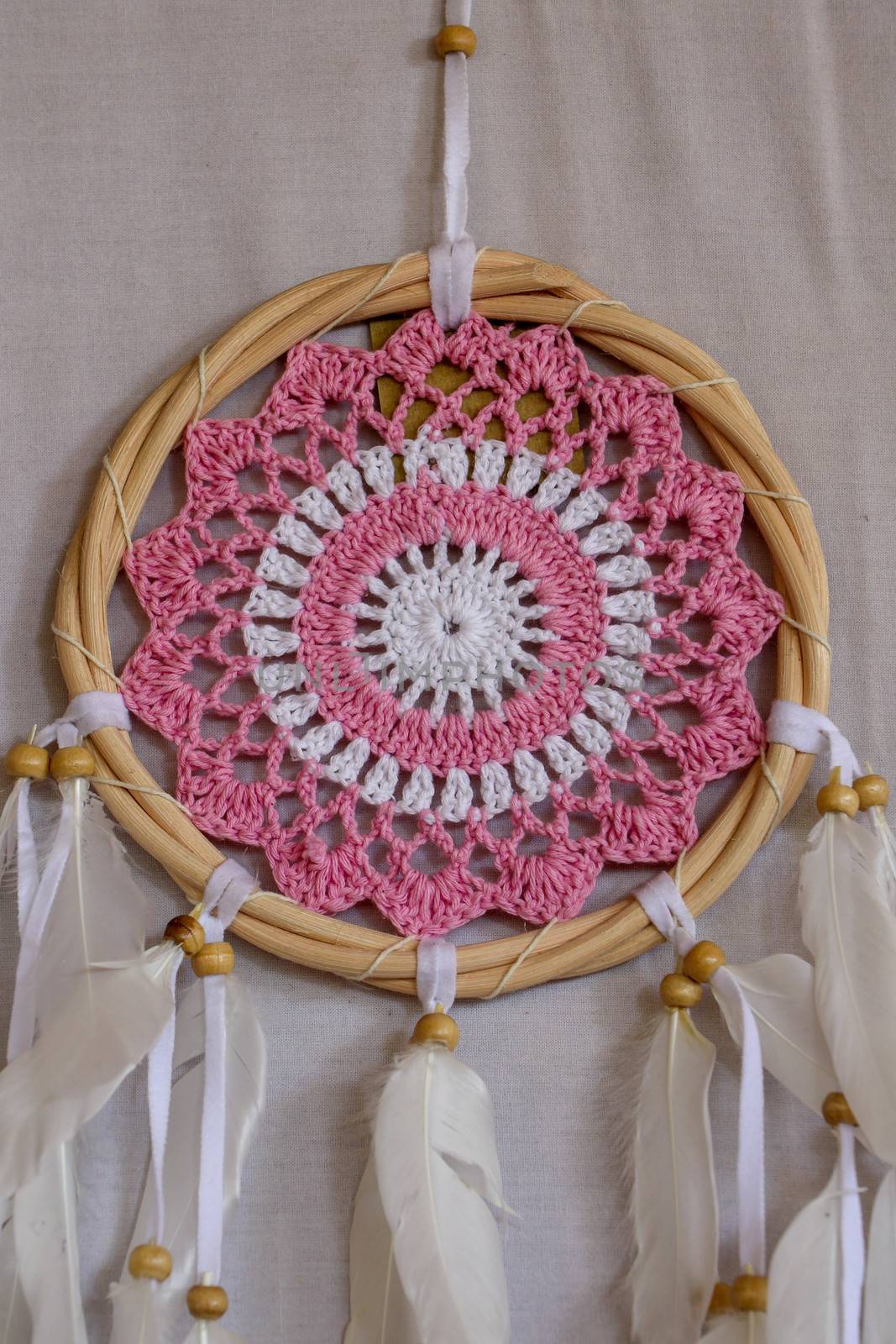 Pink ash crochet doily dream catcher close up on dark gray textured background. Texture of concrete, copy space for text. White background.