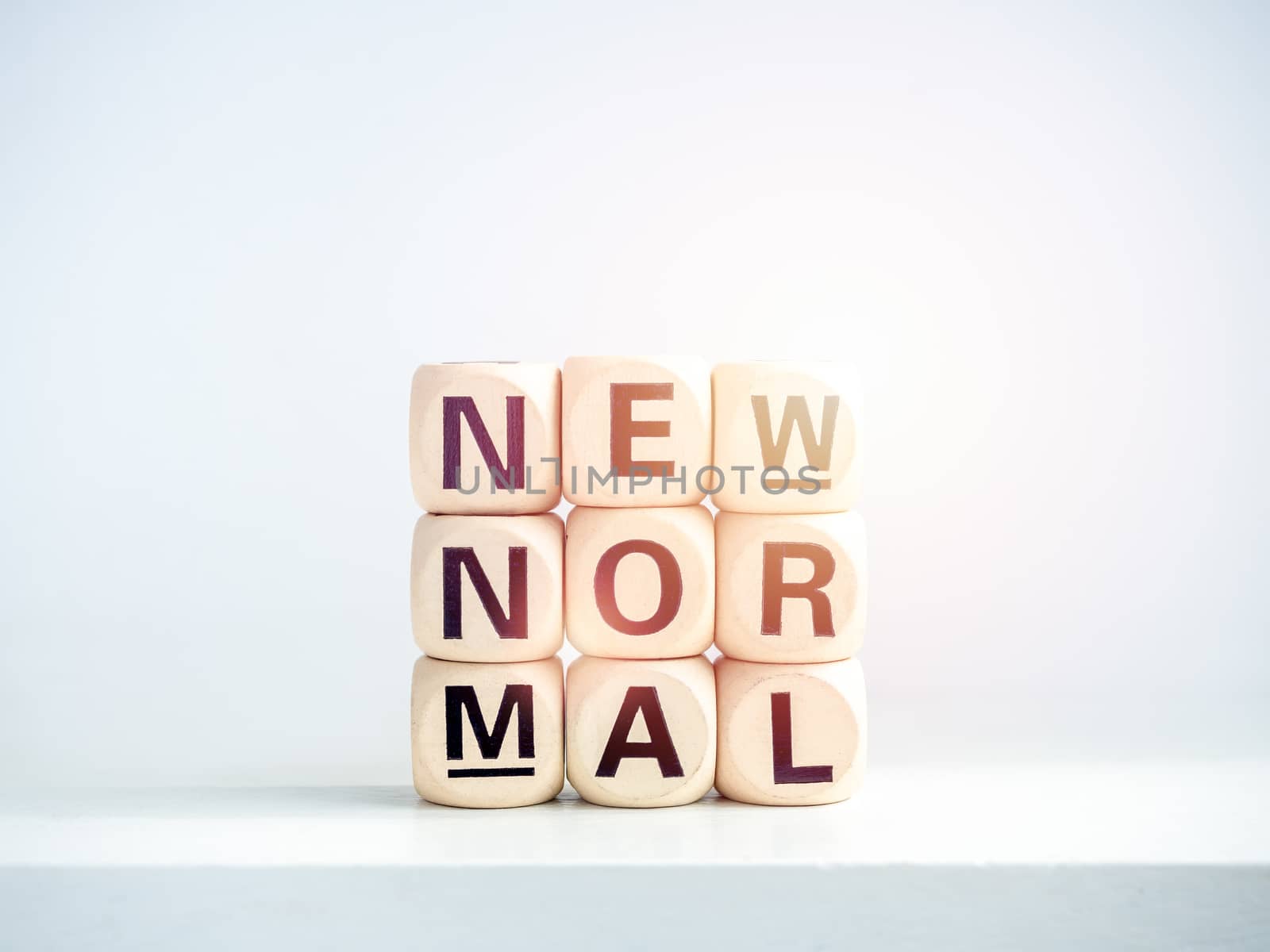 Close-up New Normal, words on wooden alphabet cube on shelf on white background. New normal after covid-19 pandemic concept.